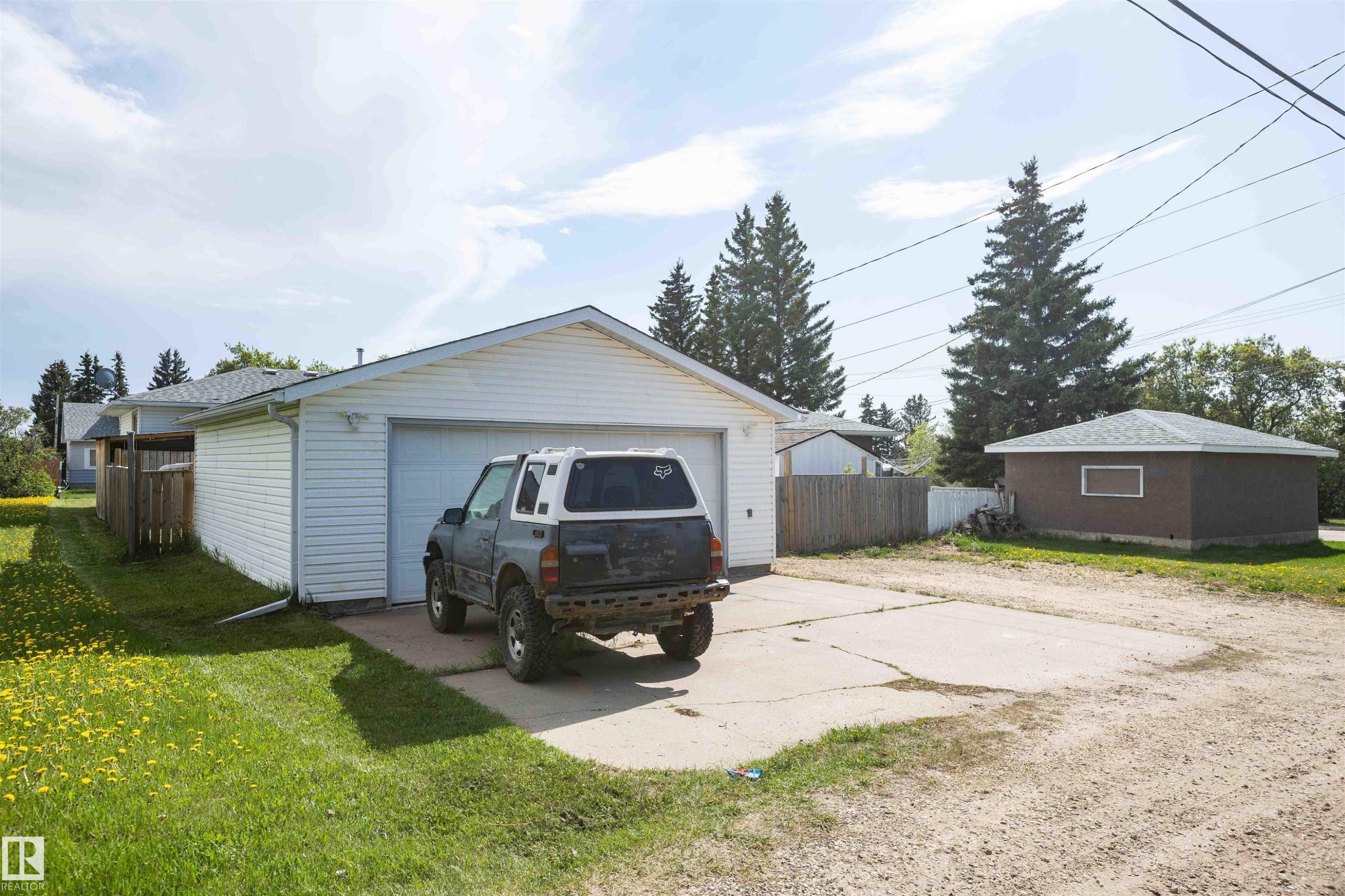 Detached two-car garage with white siding and an additional detached brown accessory building - 4414 54 Avenue, Barrhead, AB - Outdoor