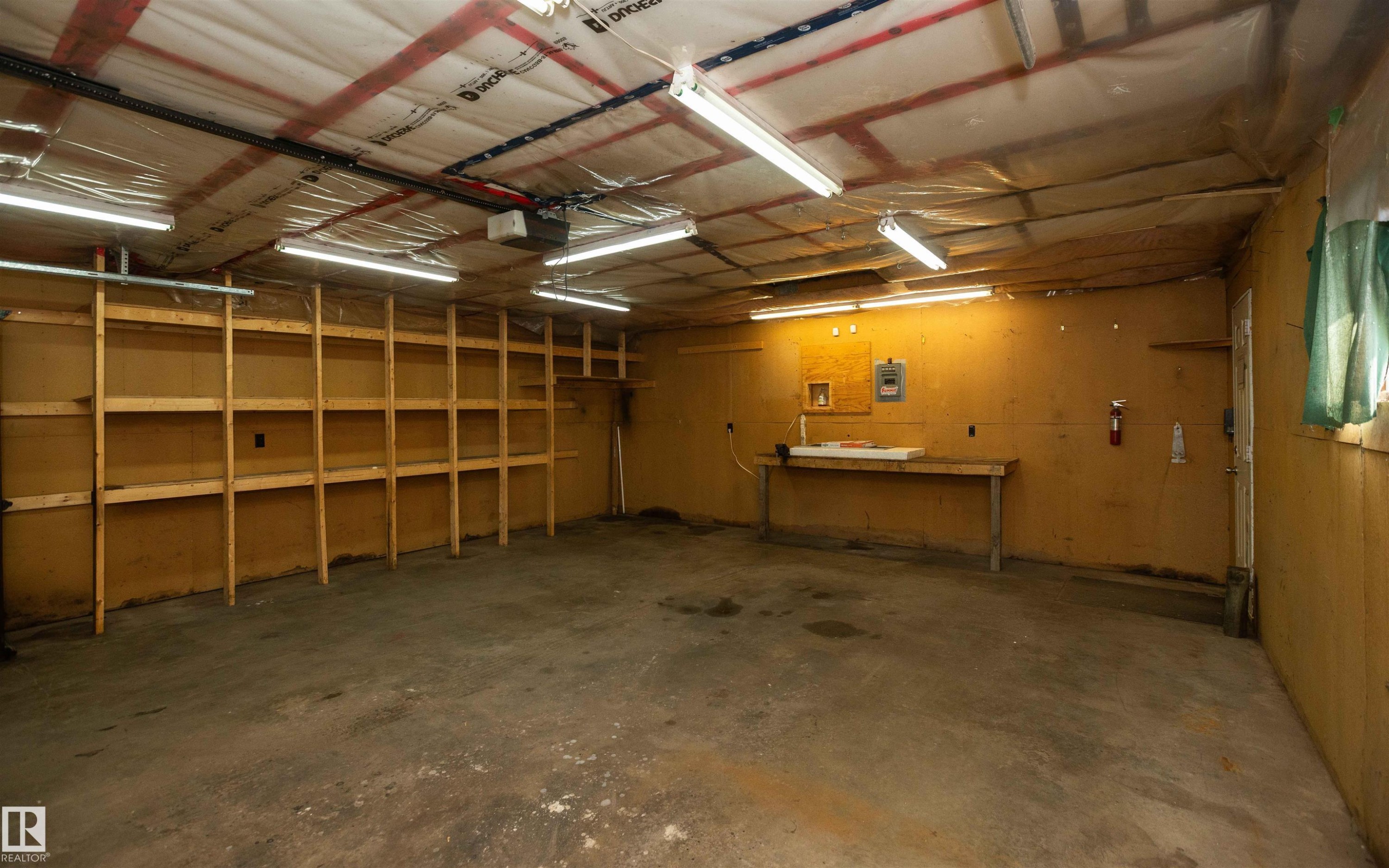 Spacious garage featuring concrete flooring and exposed ceiling rafters - 4414 54 Avenue, Barrhead, AB - Indoor Photo Showing Garage