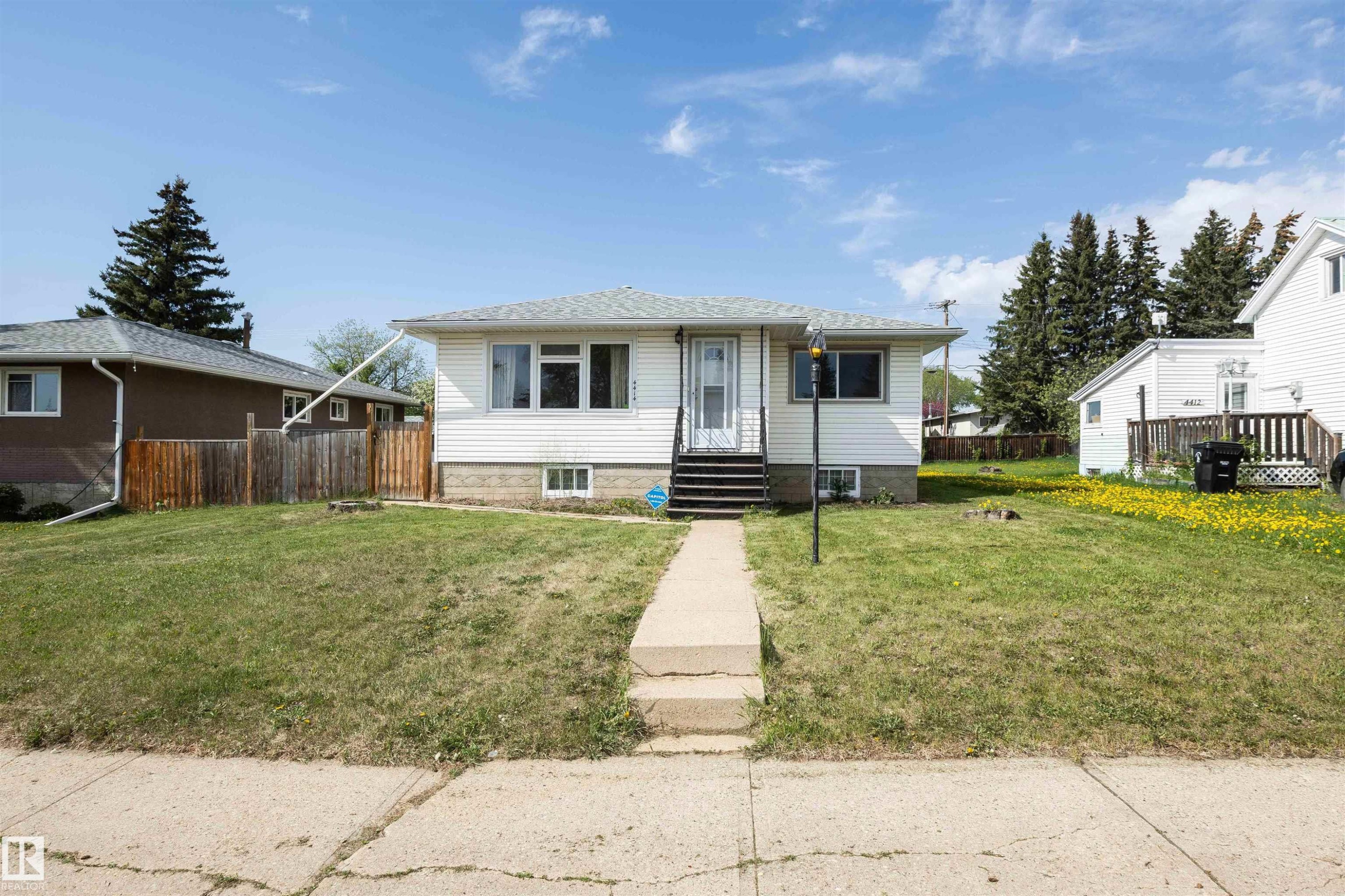 White siding exterior with a shingled roof, featuring a concrete walkway leading to the front entry - 4414 54 Avenue, Barrhead, AB - Outdoor