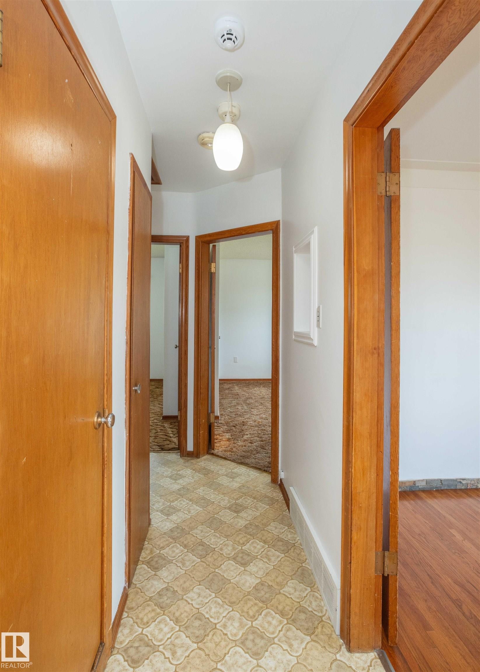 Hallway featuring patterned floor tiles and light wood-finish doors - 4414 54 Avenue, Barrhead, AB - Indoor Photo Showing Other Room