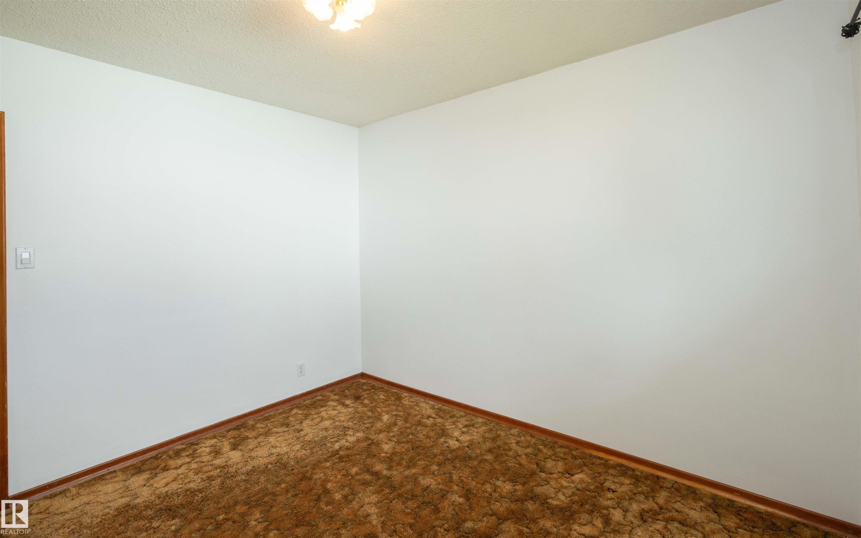 Room featuring neutral white walls, brown carpet flooring, and coordinating brown baseboards - 4414 54 Avenue, Barrhead, AB - Indoor Photo Showing Other Room