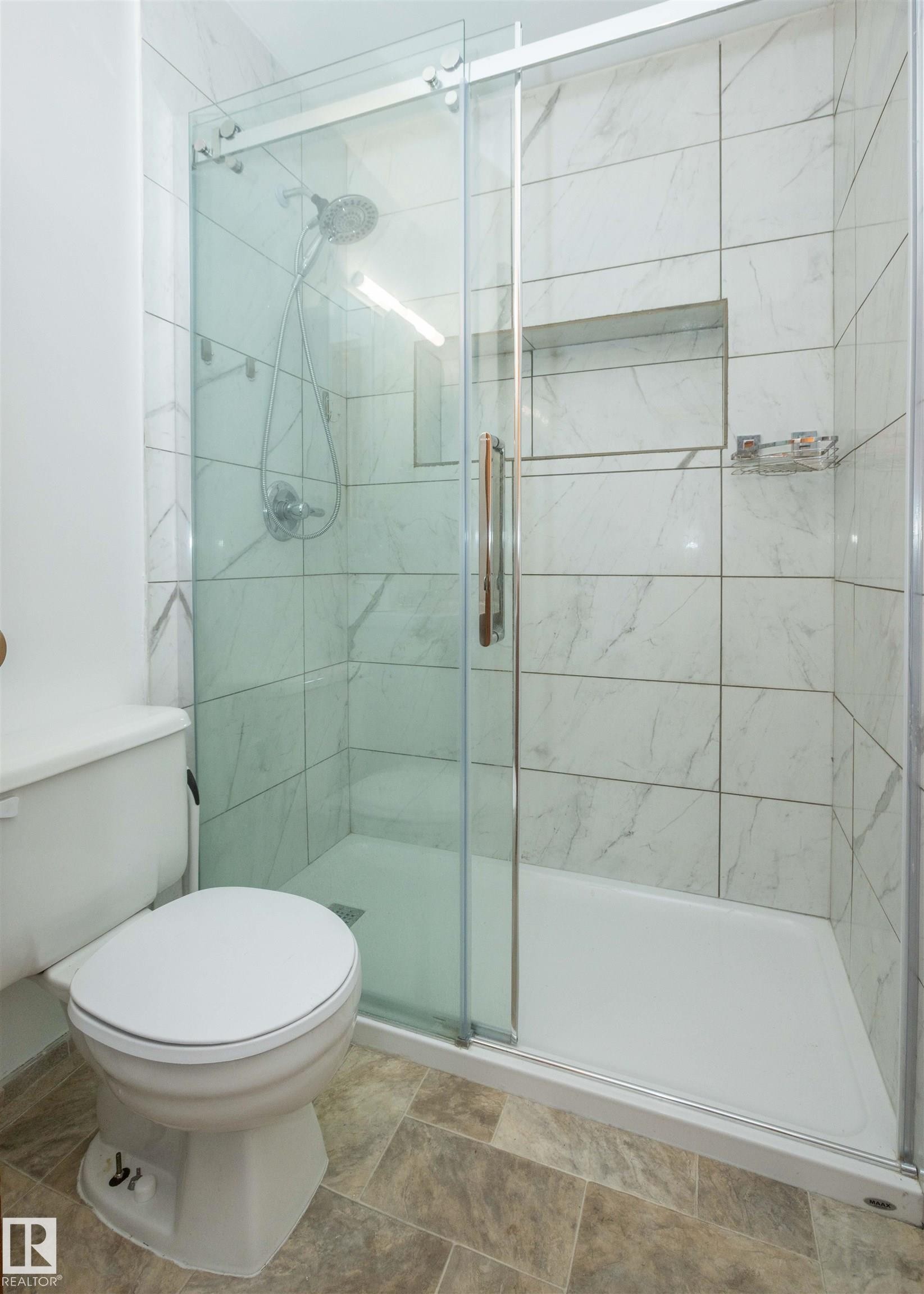 Glass-enclosed shower with white marble-look subway tile and a built-in shower niche - 4414 54 Avenue, Barrhead, AB - Indoor Photo Showing Bathroom