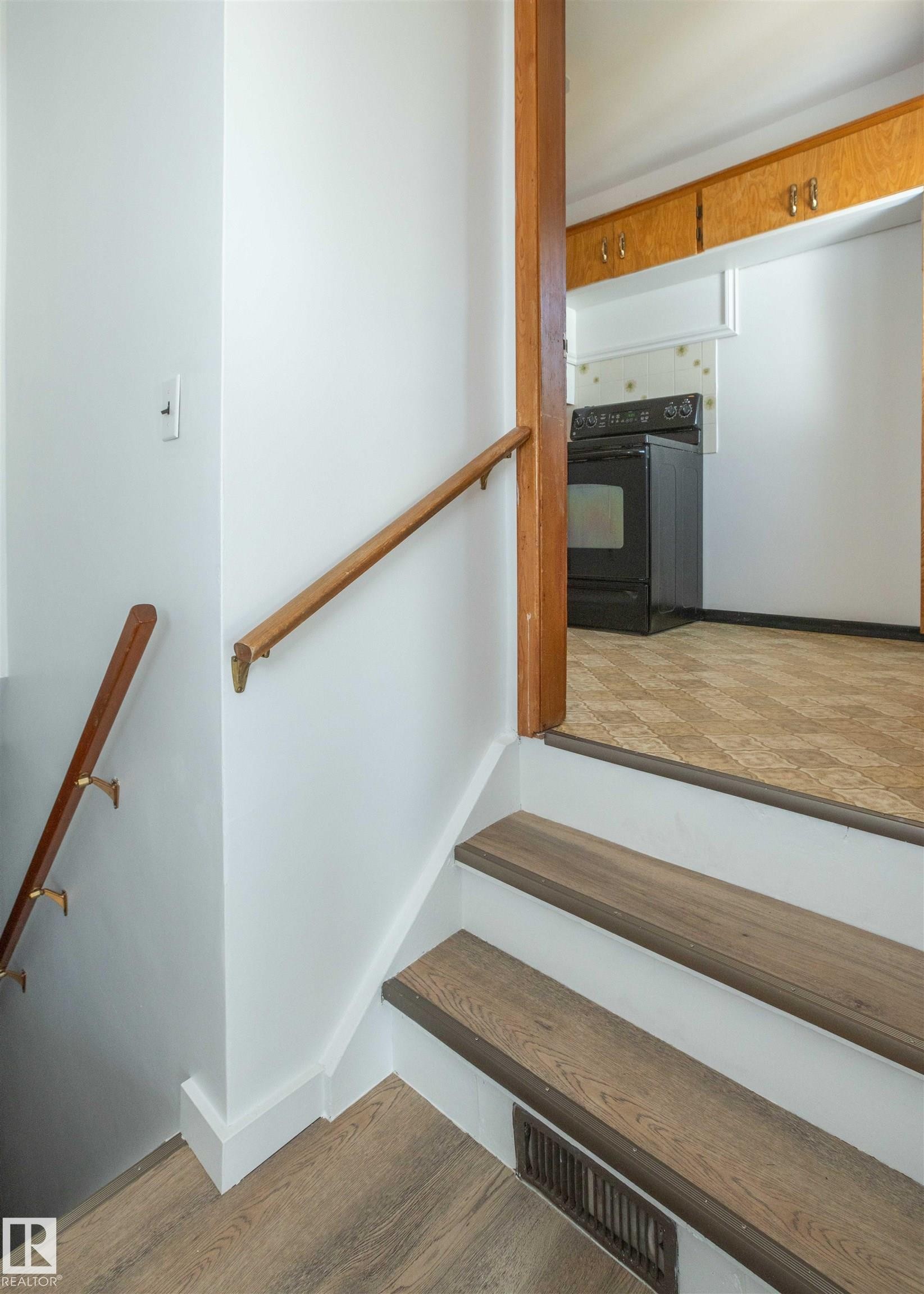 Wood-finish stair treads with painted risers and wood handrails - 4414 54 Avenue, Barrhead, AB - Indoor Photo Showing Other Room