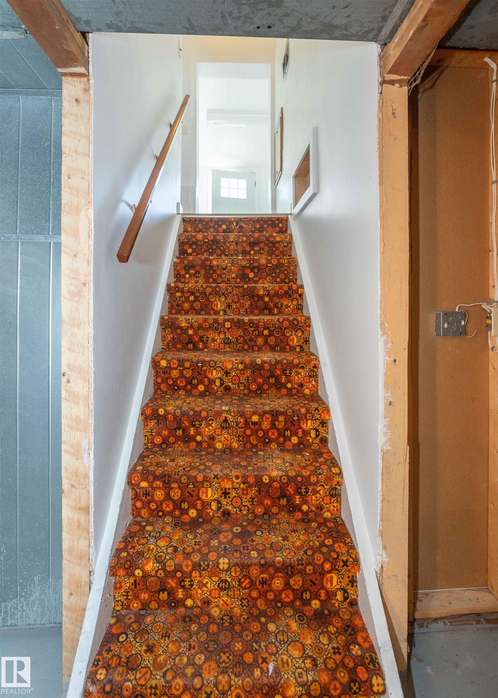Carpeted staircase with white risers and a wooden handrail - 4414 54 Avenue, Barrhead, AB - Indoor Photo Showing Other Room
