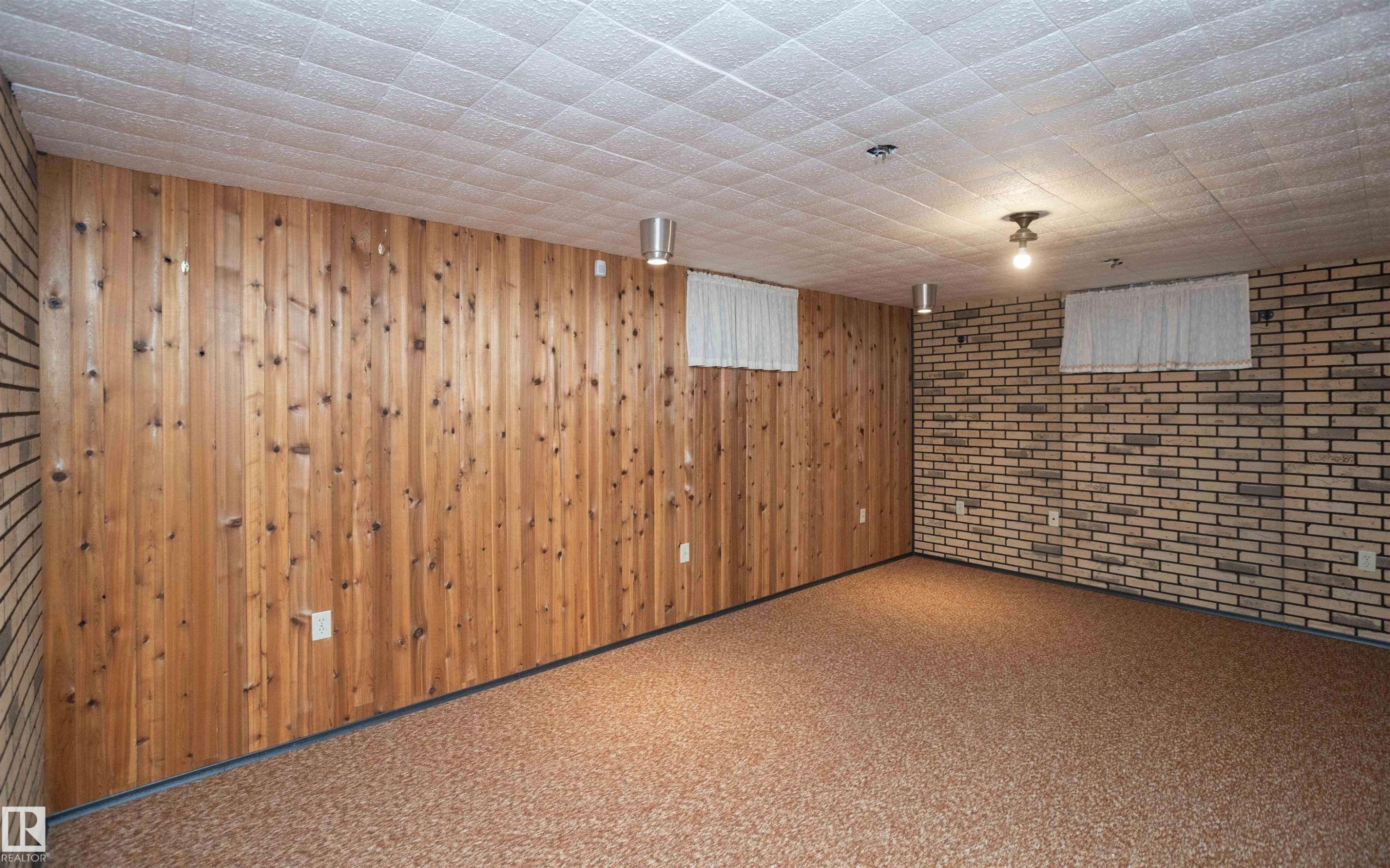 Room featuring wood paneling, brick accent wall, textured ceiling, and patterned flooring - 4414 54 Avenue, Barrhead, AB - Indoor Photo Showing Other Room