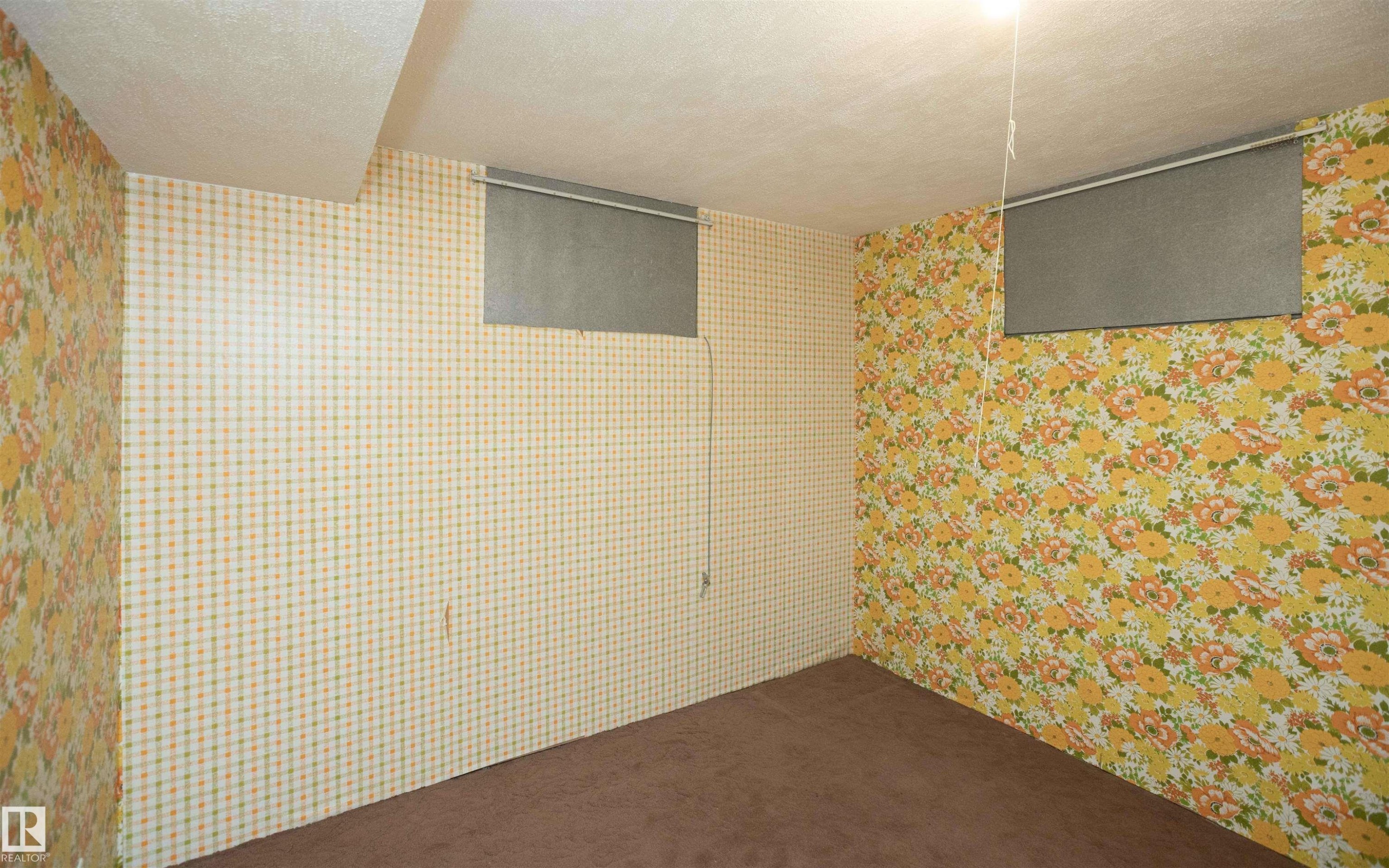 Finished room with dual window openings, brown carpet flooring, and two distinct wallpaper patterns - 4414 54 Avenue, Barrhead, AB - Indoor Photo Showing Other Room
