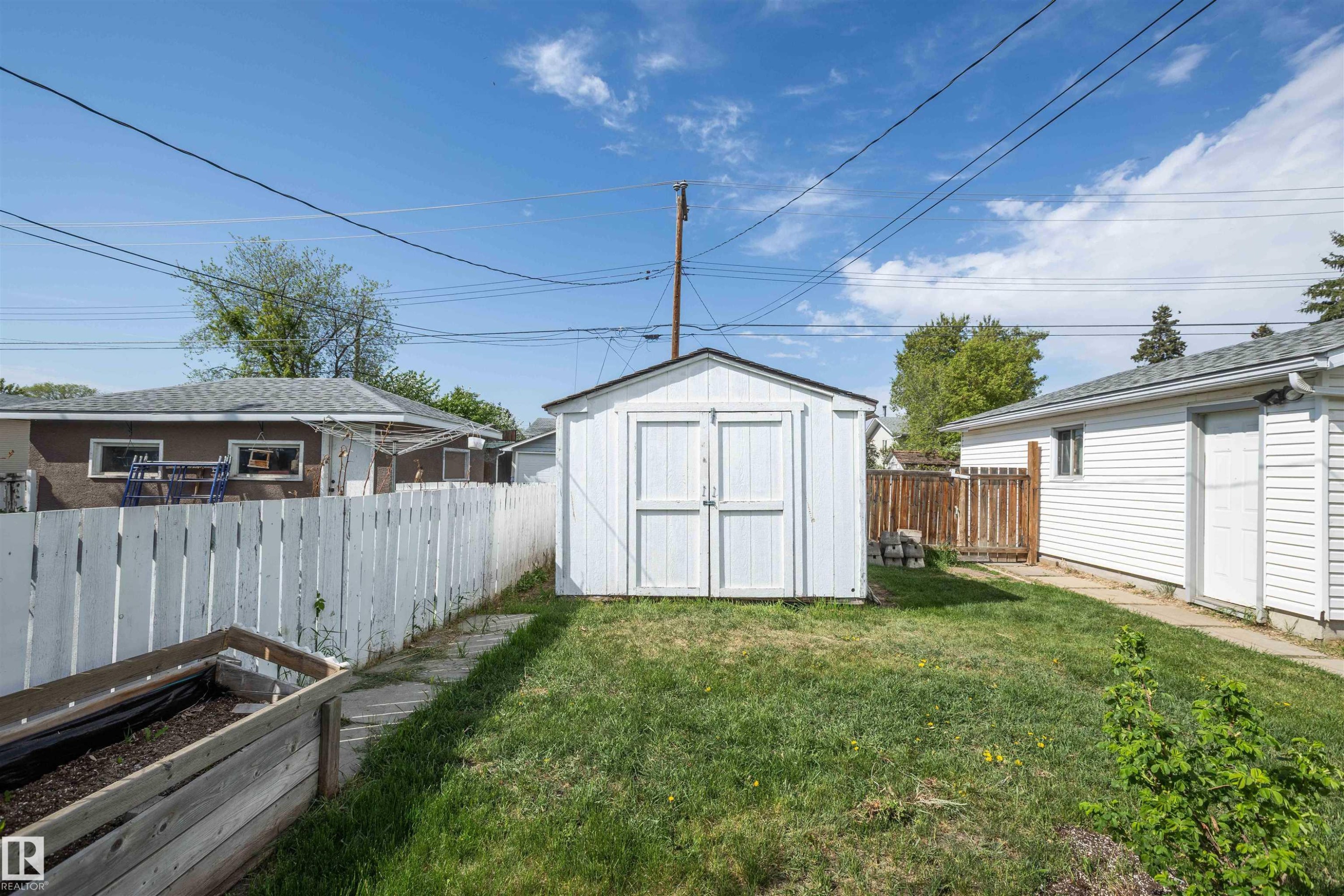 Expansive grassy area featuring a white storage shed and perimeter fencing - 4414 54 Avenue, Barrhead, AB - Outdoor