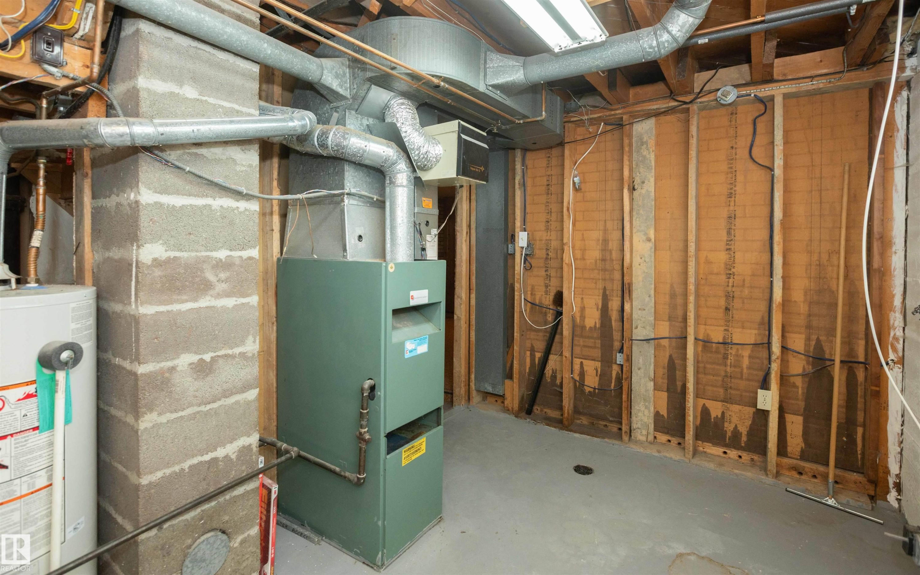 Basement utility area featuring a furnace, water heater, concrete block column, exposed wood framing, and concrete flooring - 4414 54 Avenue, Barrhead, AB - Indoor Photo Showing Basement