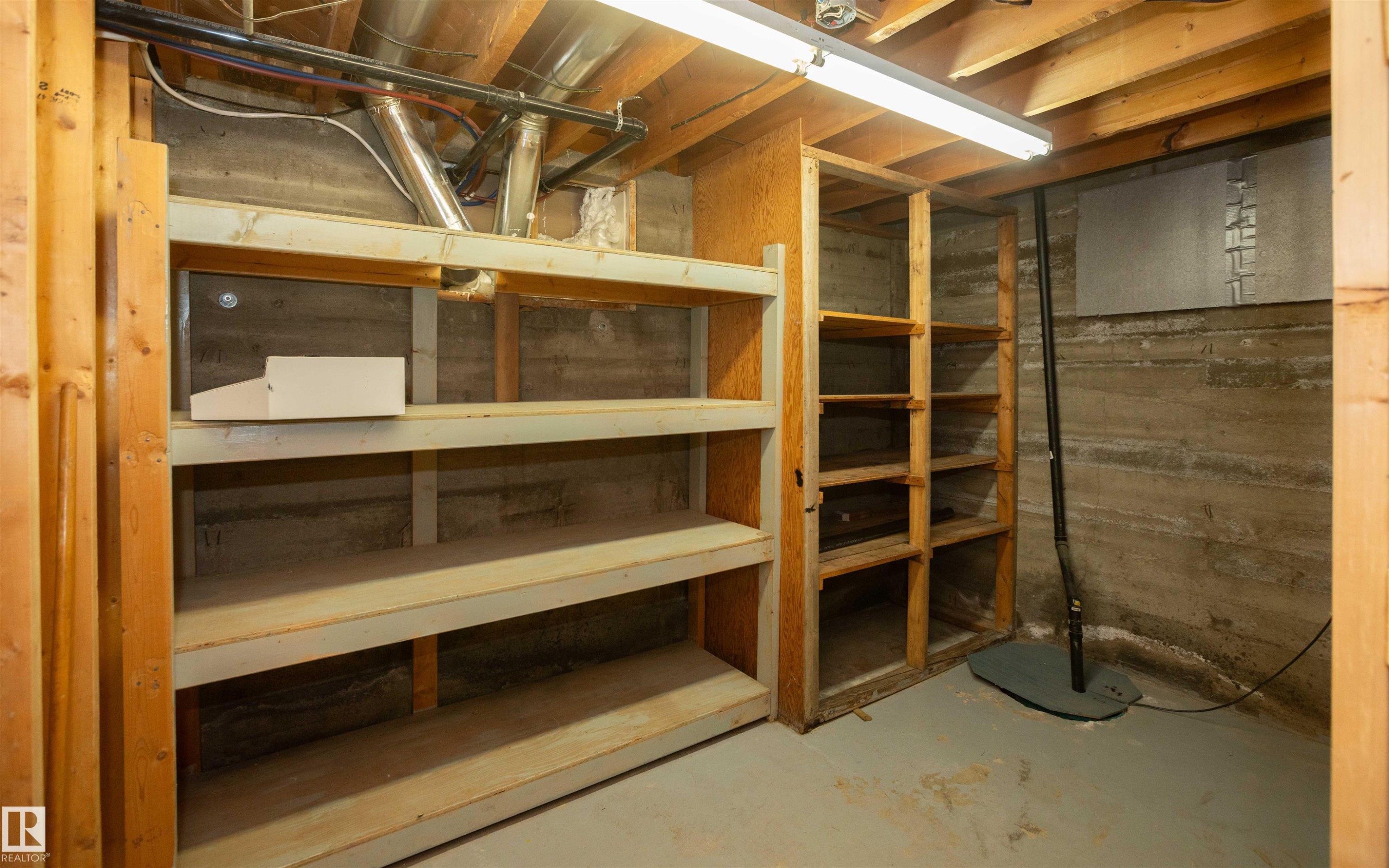 Concrete foundation walls with exposed wood framing and built-in shelving - 4414 54 Avenue, Barrhead, AB - Indoor Photo Showing Basement