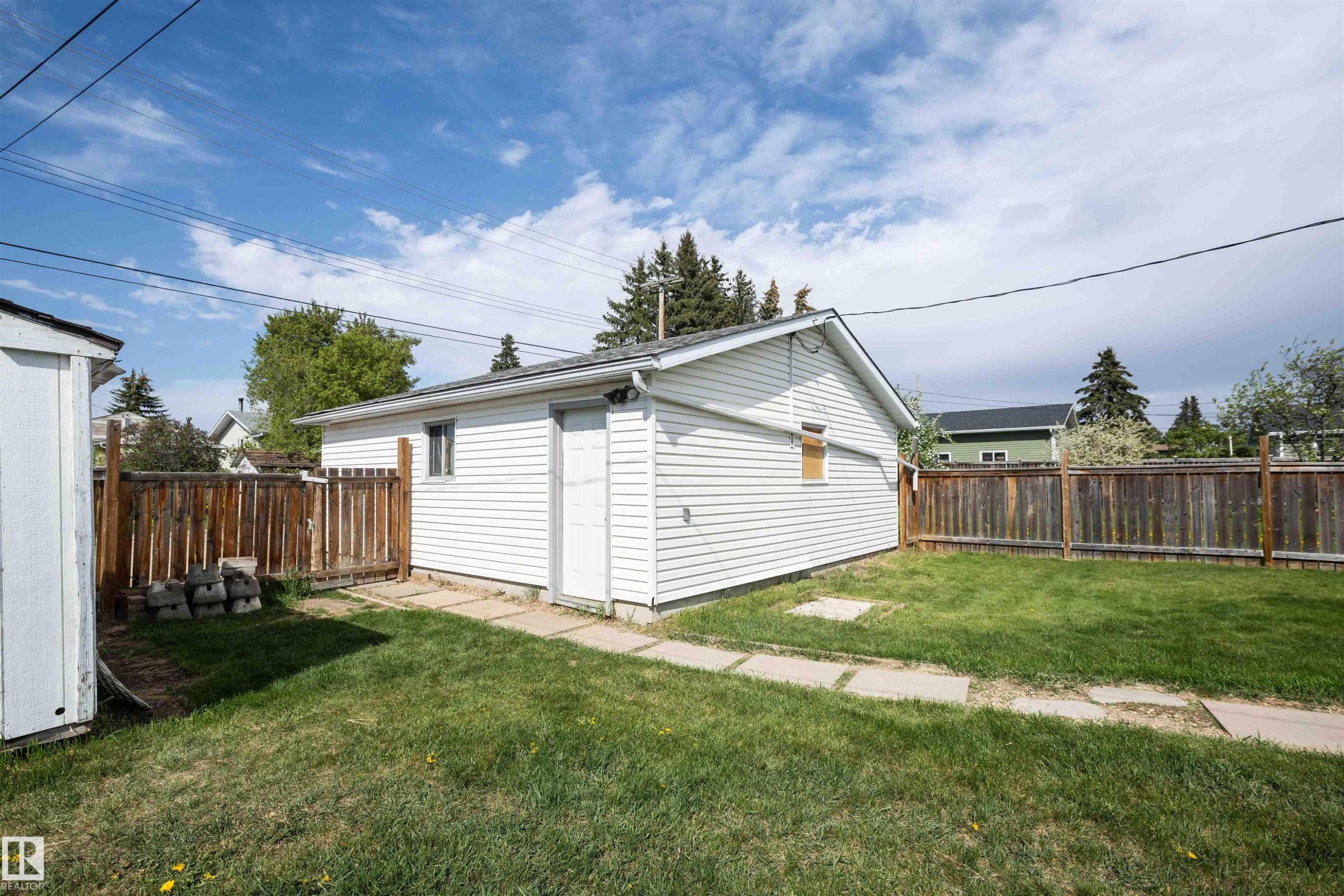 Detached garage featuring white siding, a side entry door, and a single window - 4414 54 Avenue, Barrhead, AB - Outdoor