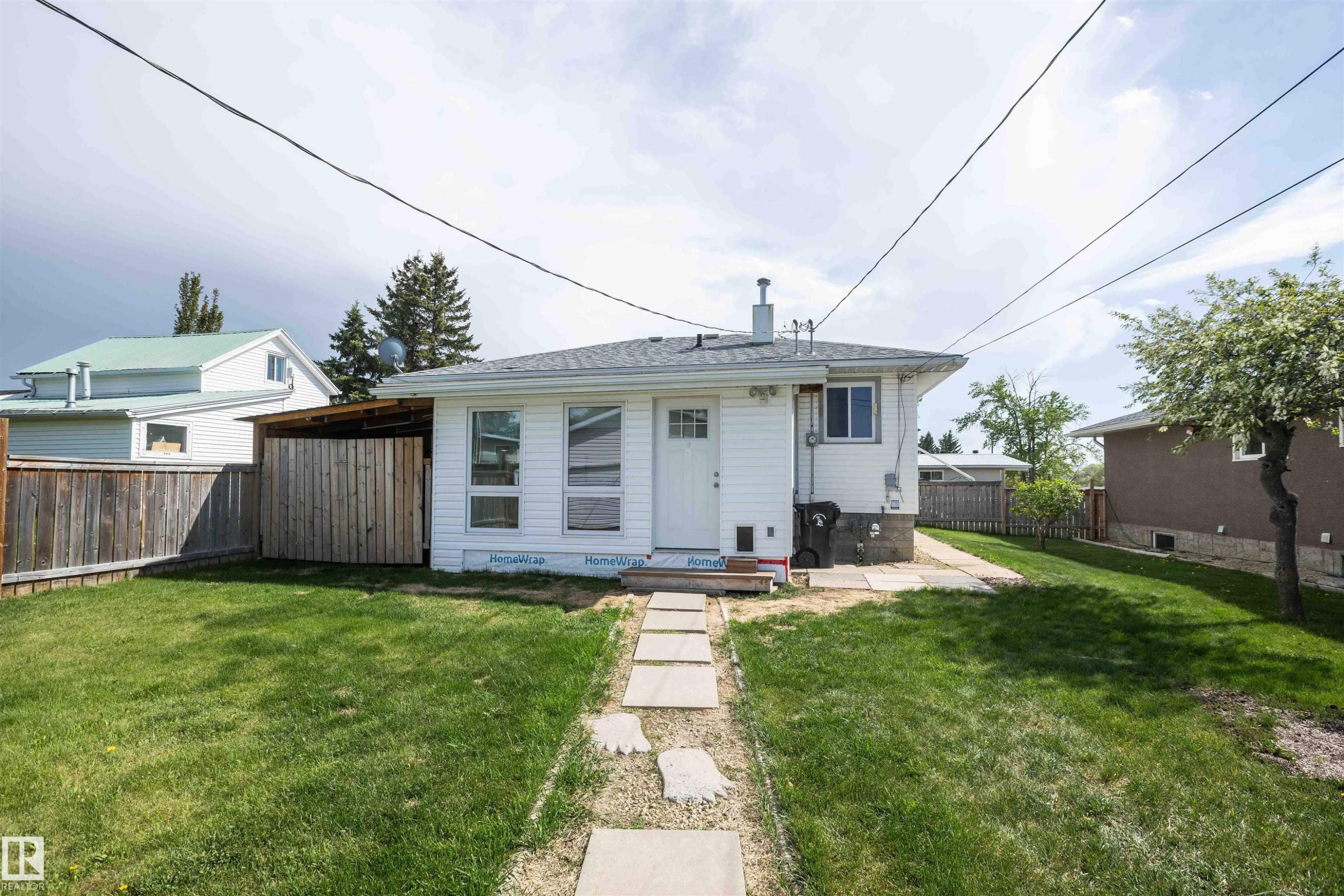 White exterior with a shingled roof and a stone pathway leading to the entrance - 4414 54 Avenue, Barrhead, AB - Outdoor