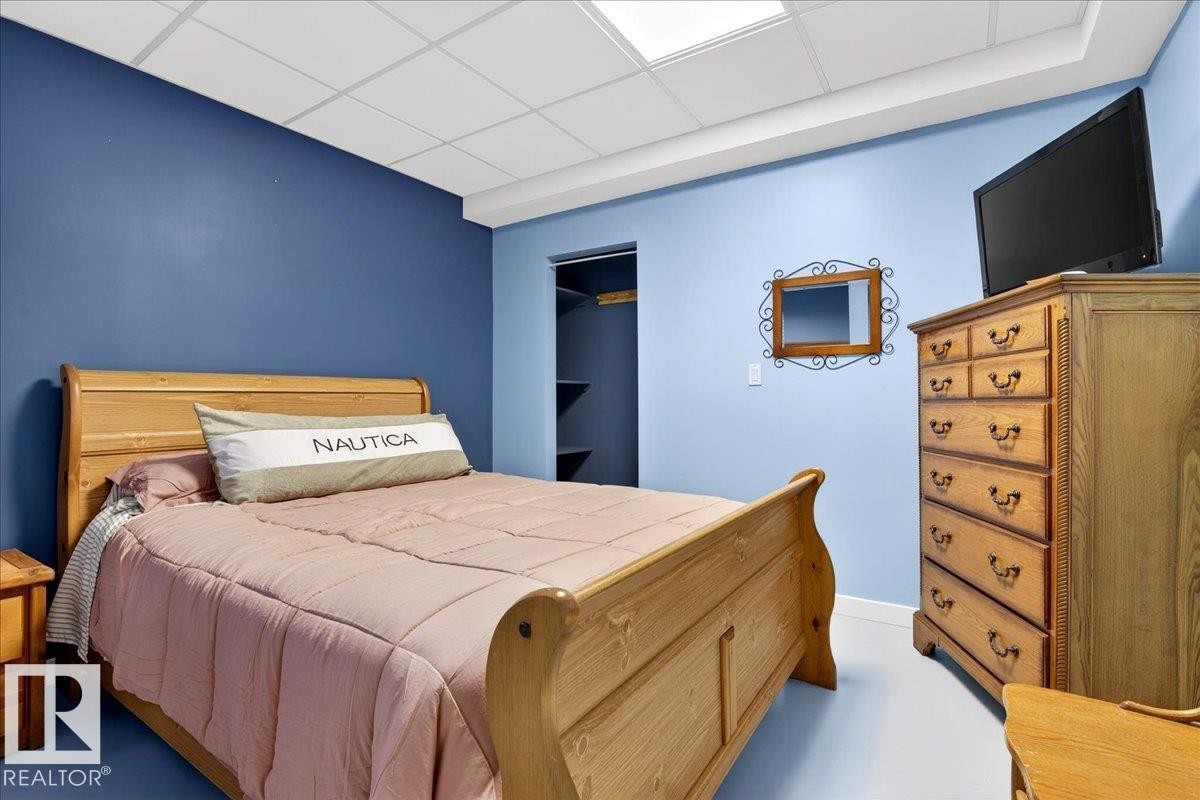 Room featuring a drop ceiling with integrated lighting, two-tone wall paint, a built-in closet with shelving, and light-toned flooring - 5019 48 Avenue, Chipman, AB - Indoor Photo Showing Bedroom