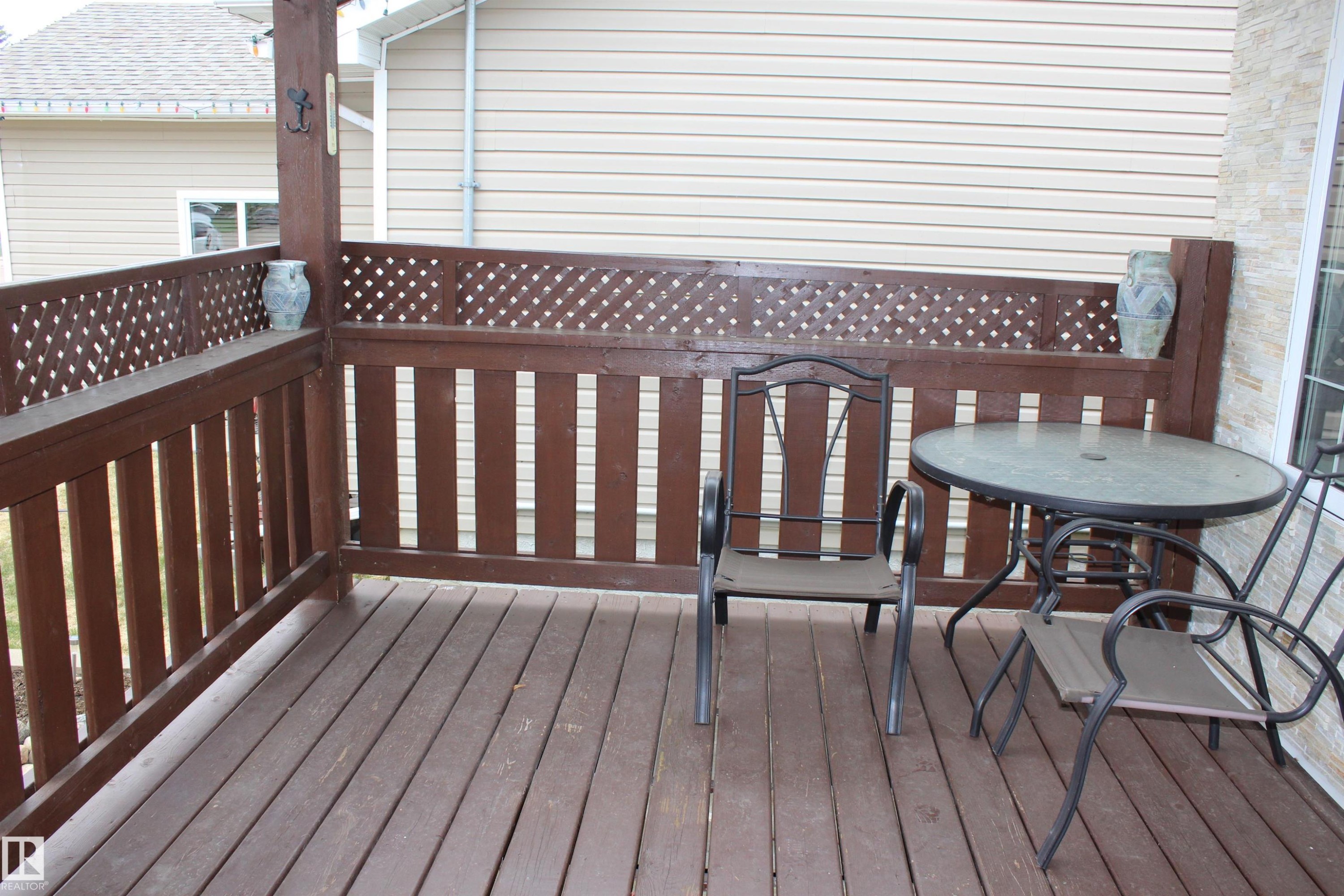 Spacious outdoor deck featuring wood flooring and a sturdy wood railing with decorative lattice accents - 5019 48 Avenue, Chipman, AB - Outdoor With Deck Patio Veranda With Exterior