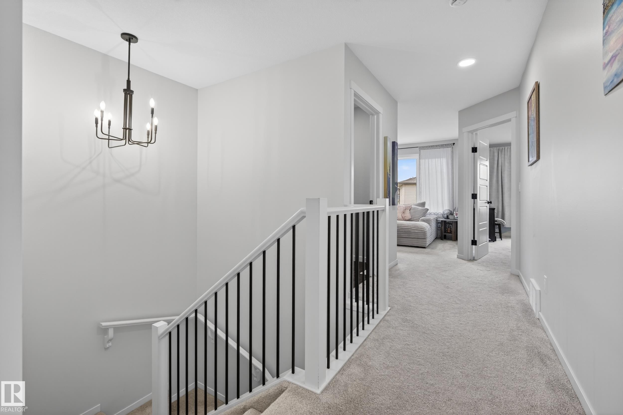 Modern black chandelier illuminating a stairway with white railings and black metal spindles - 22836 94 Avenue, Edmonton, AB