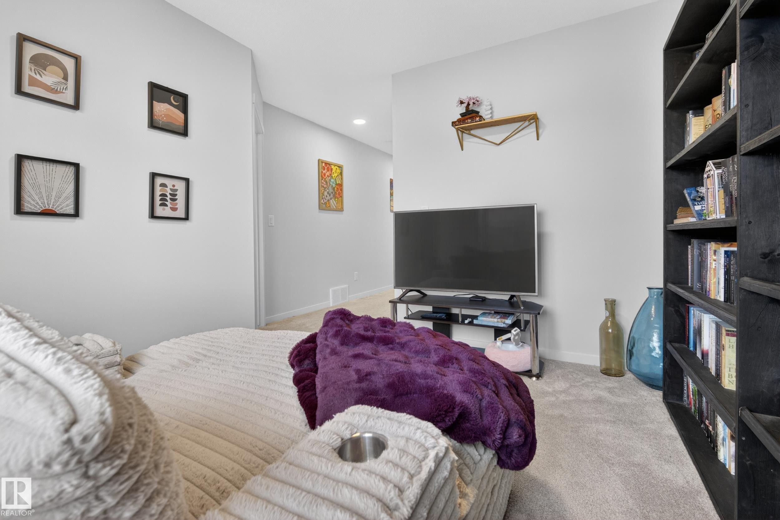 Carpeted interior space featuring a built-in dark wood shelving unit, a wall-mounted shelving accent, and light gray wall paint - 22836 94 Avenue, Edmonton, AB