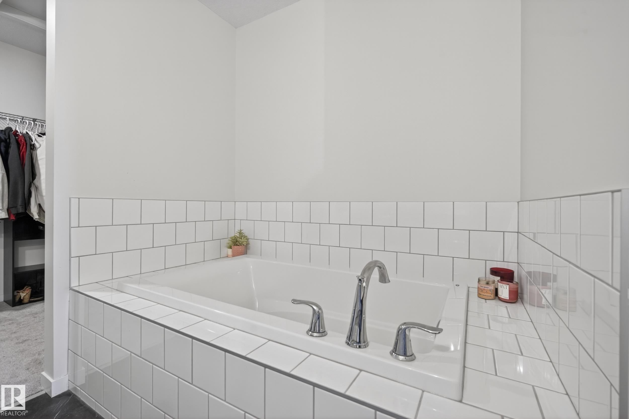 Built-in soaking tub featuring white subway tile surround with contrasting grout, chrome fixtures, and a tiled ledge - 22836 94 Avenue, Edmonton, AB