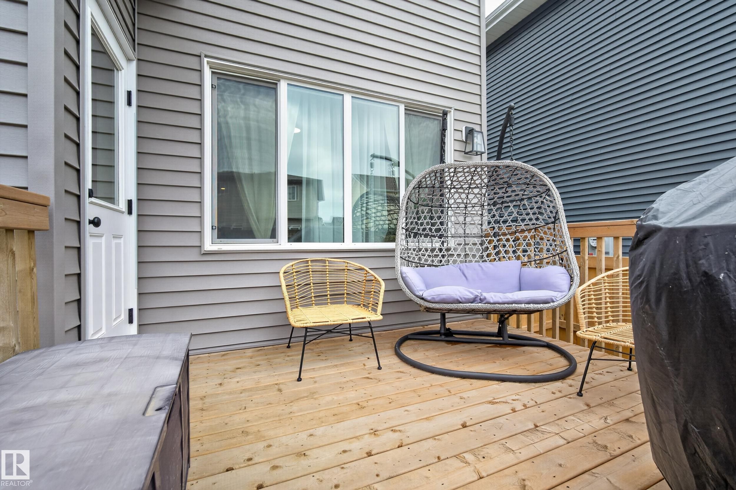 Wood-finish deck with grey siding and a white exterior door - 22836 94 Avenue, Edmonton, AB