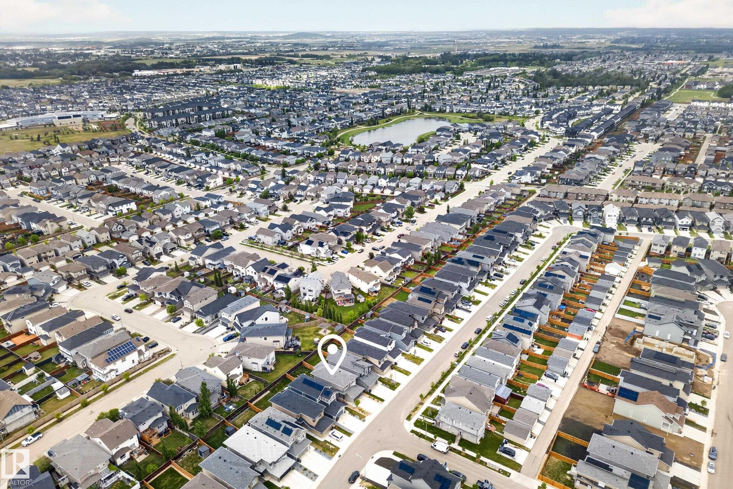 Aerial view showcasing an established residential community with a mix of housing styles and a central pond feature - 22836 94 Avenue, Edmonton, AB
