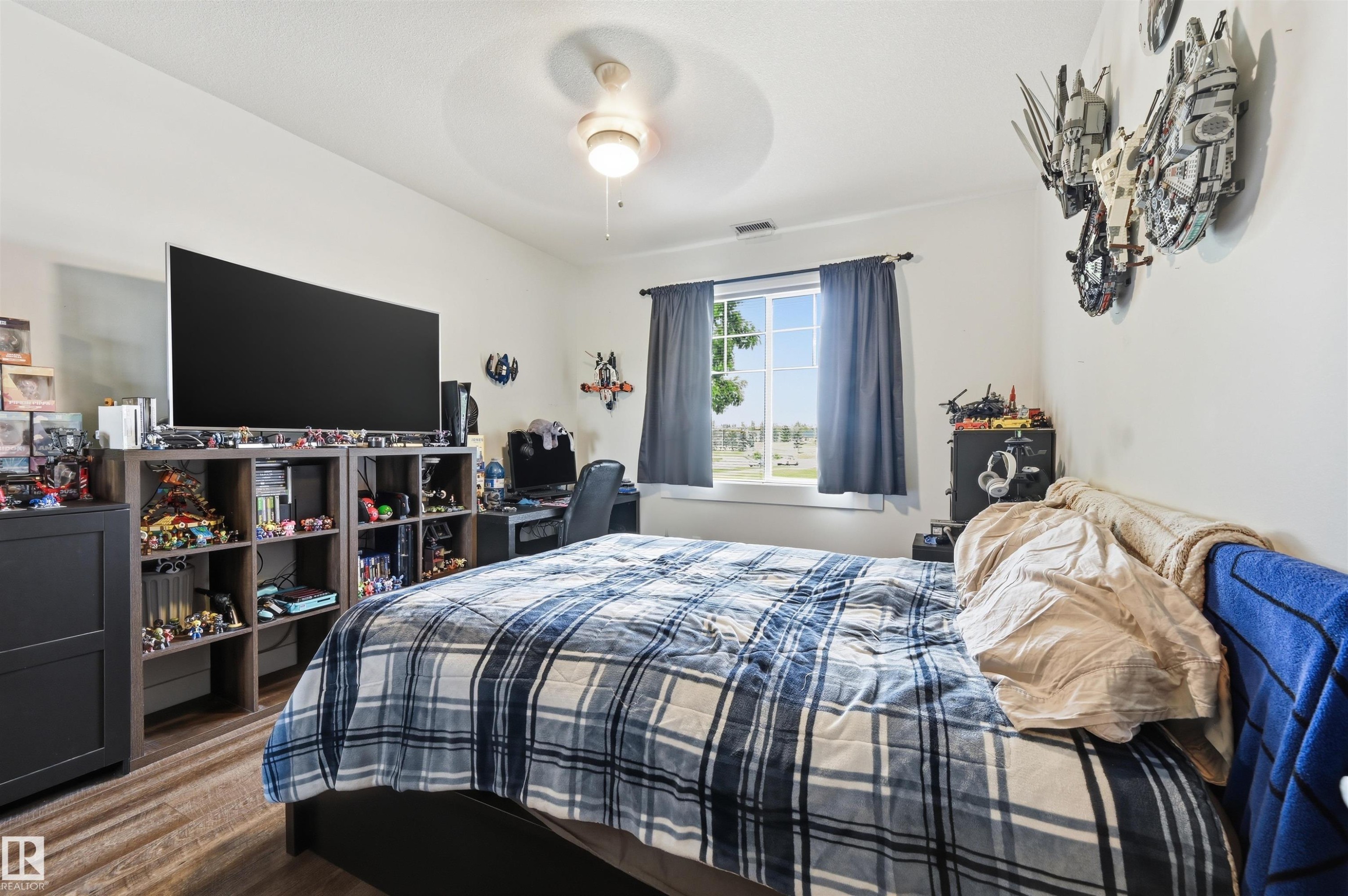 Spacious room with a ceiling fan, a window, wood-finish flooring, and white walls - 217 2503 Hanna Crescent, Edmonton, AB