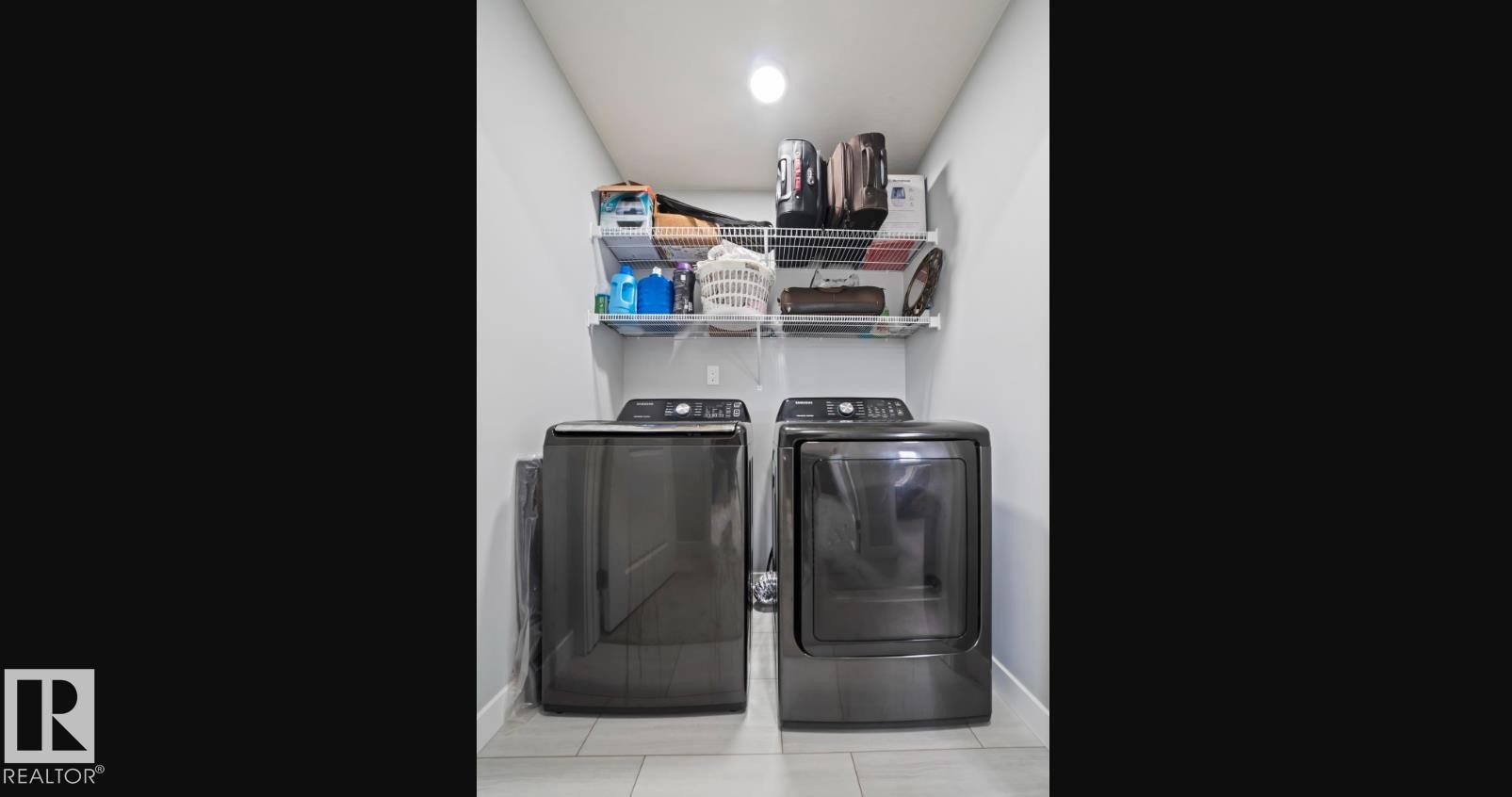 Laundry area featuring a ceiling-mounted light fixture, light gray walls, light tile flooring, and integrated wire shelving - 2153 Maple Road, Edmonton, AB
