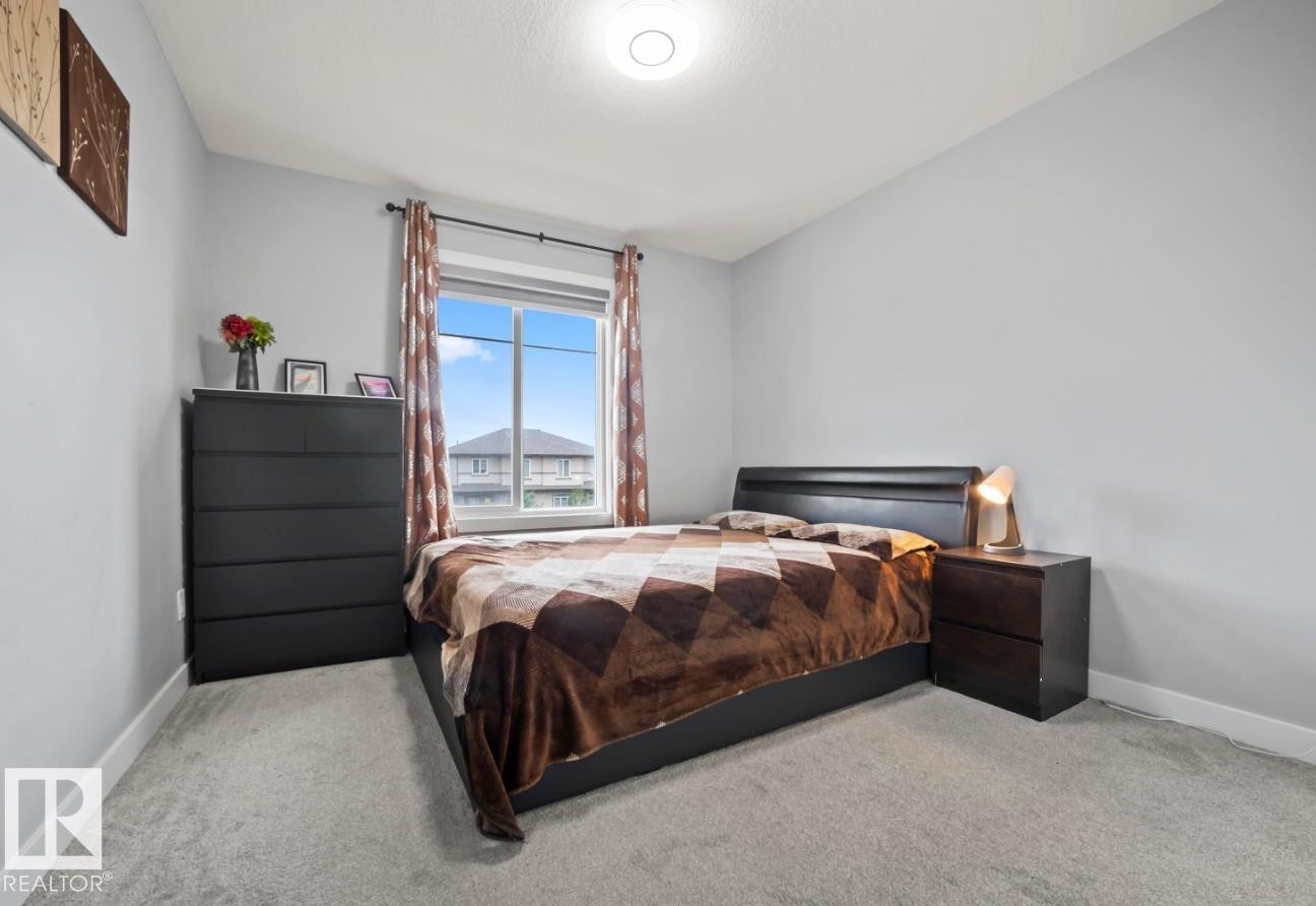 Carpeted room with a large window, a flush-mount ceiling light, and light gray walls - 2153 Maple Road, Edmonton, AB