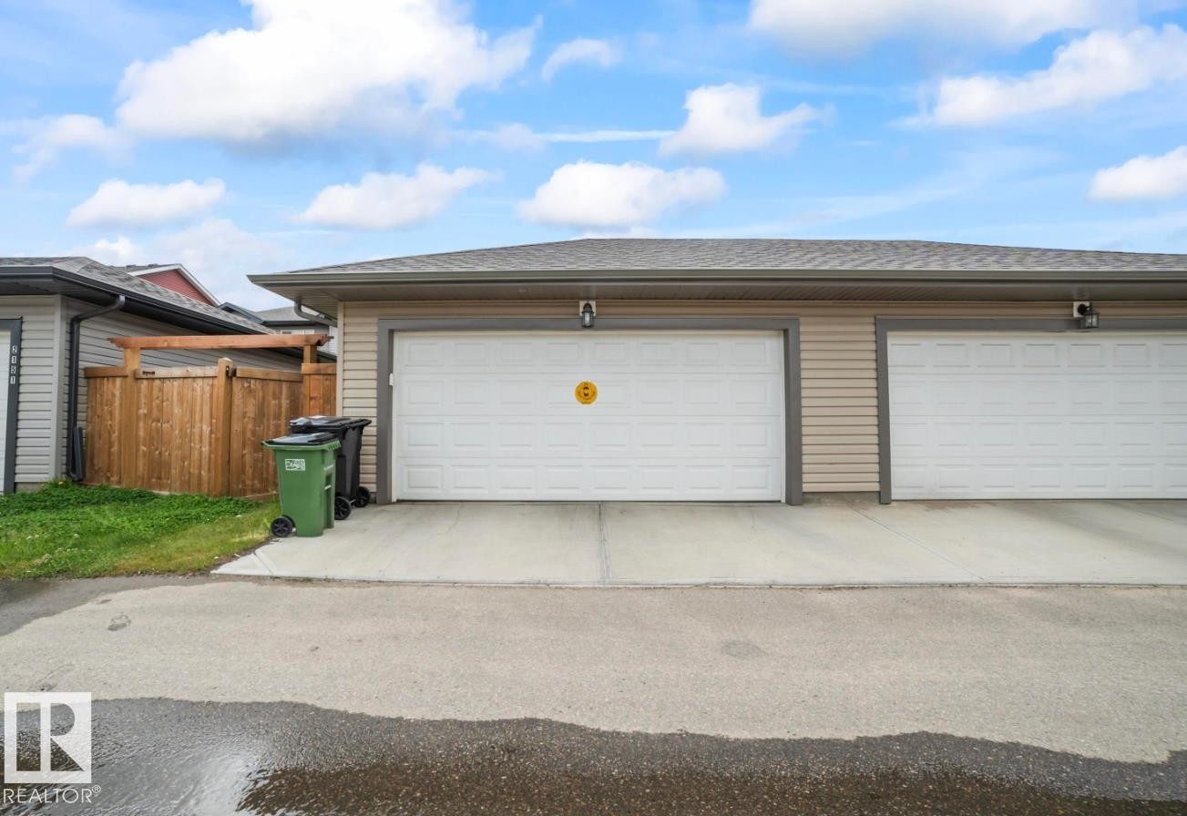 Attached two-car garage featuring individual white panel doors and exterior lighting fixtures - 2153 Maple Road, Edmonton, AB