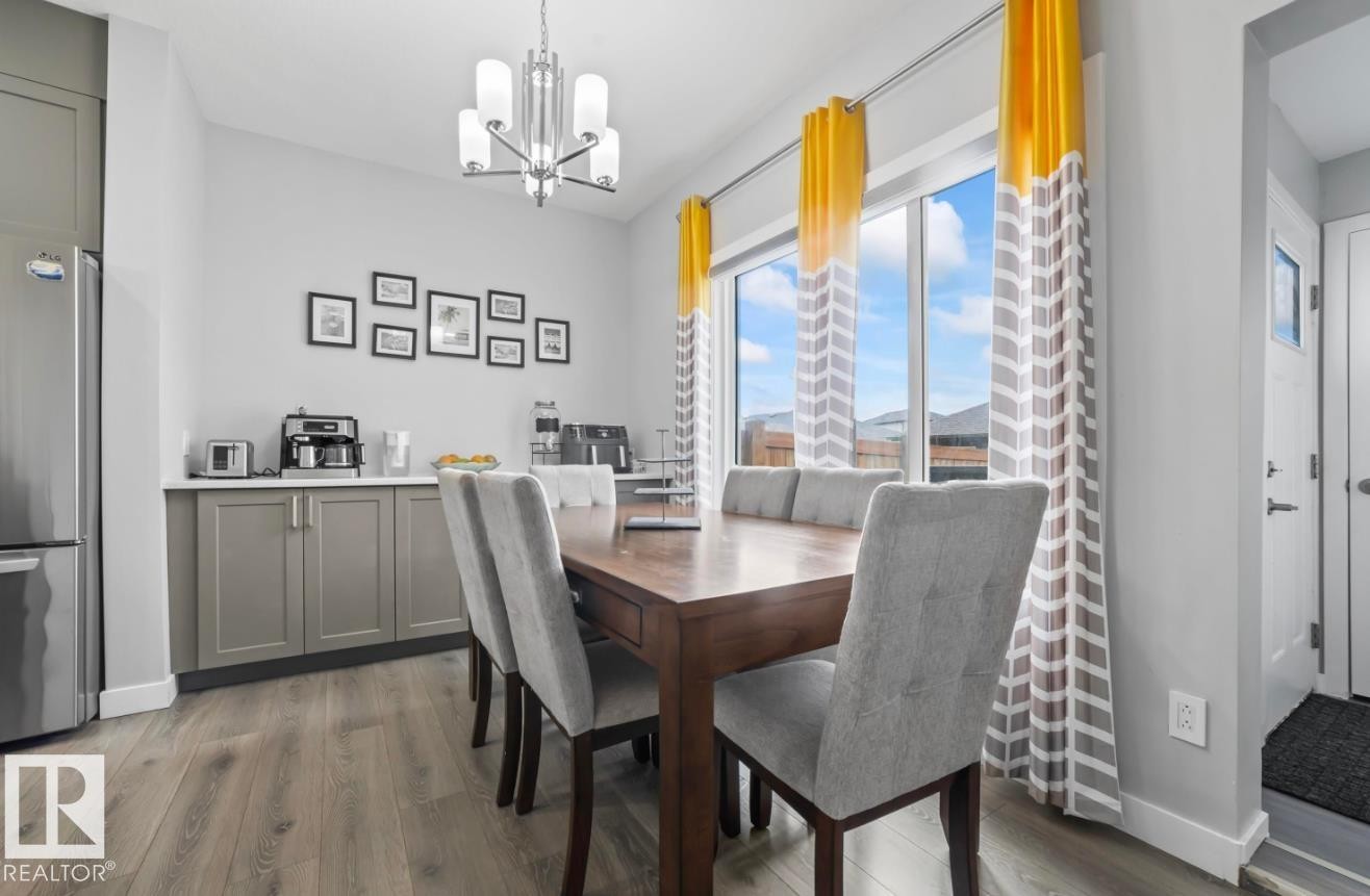 Dining area with wood-finish flooring, a contemporary chandelier, and a built-in buffet with light gray cabinetry and a white countertop - 2153 Maple Road, Edmonton, AB