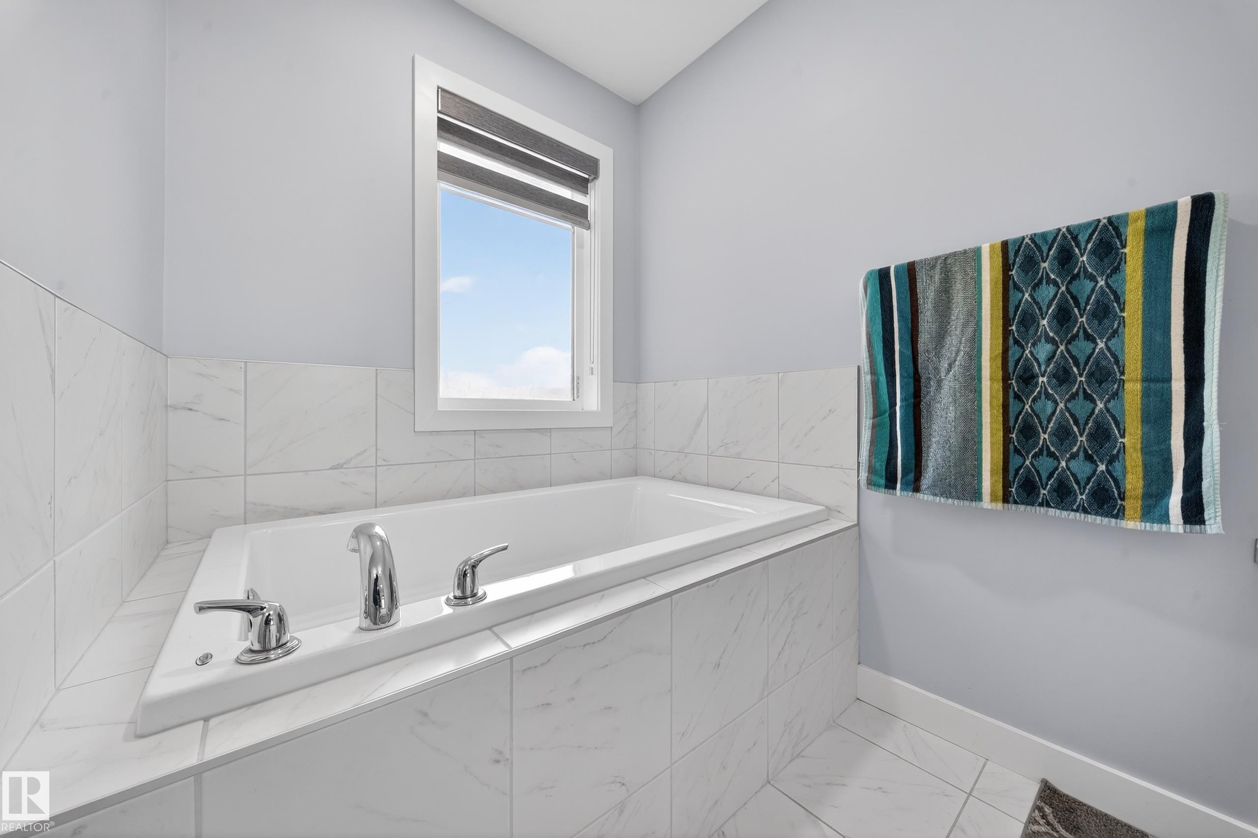 Built-in soaking tub with chrome fixtures, surrounded by white tile and light-toned walls - 2084 Graydon Hill, Edmonton, AB