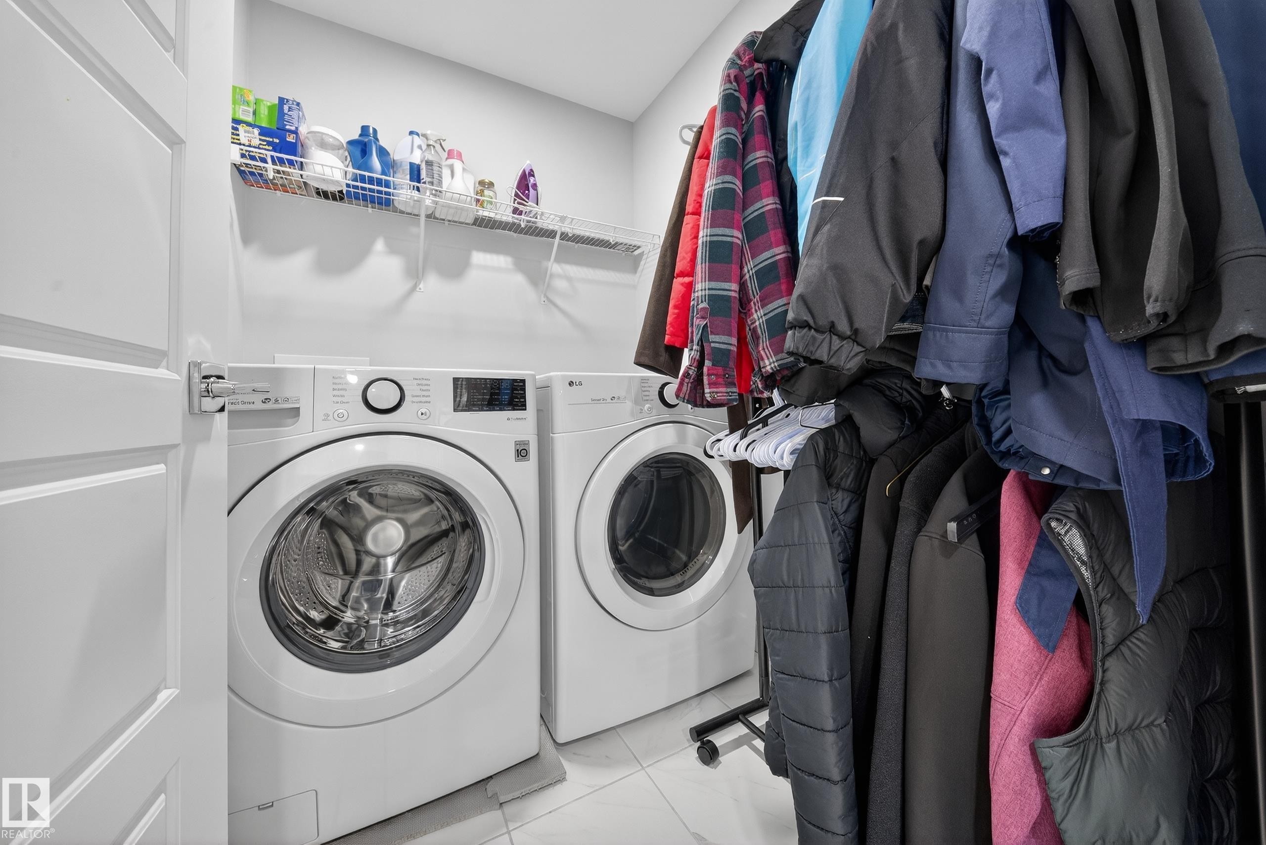 Laundry area featuring a front-loading washer and dryer set, white wall shelving, and light-toned flooring - 2084 Graydon Hill, Edmonton, AB
