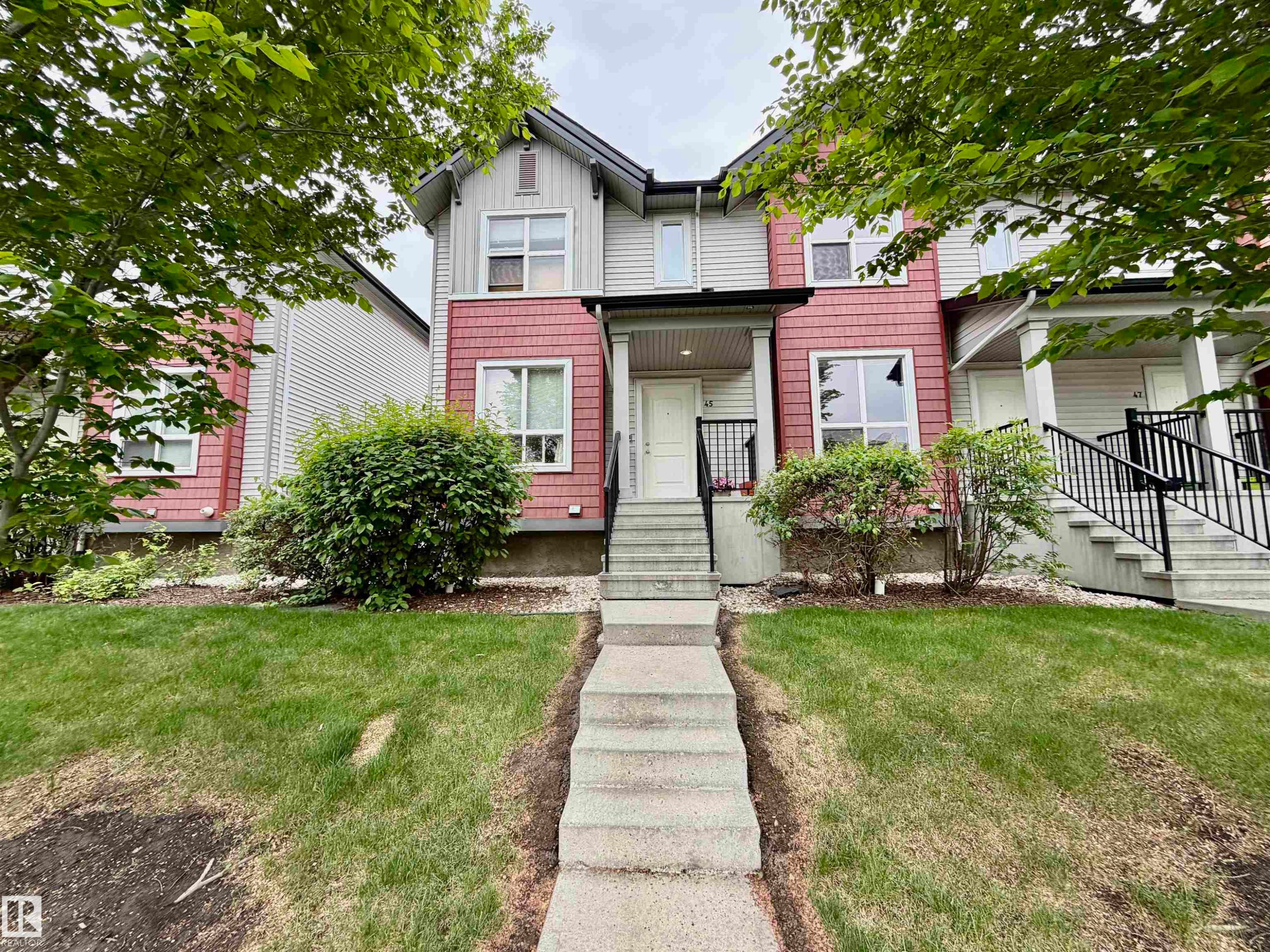 Townhome exterior featuring a two-story façade with horizontal siding and shingle accents - 45 6075 Schonsee Way, Edmonton, AB
