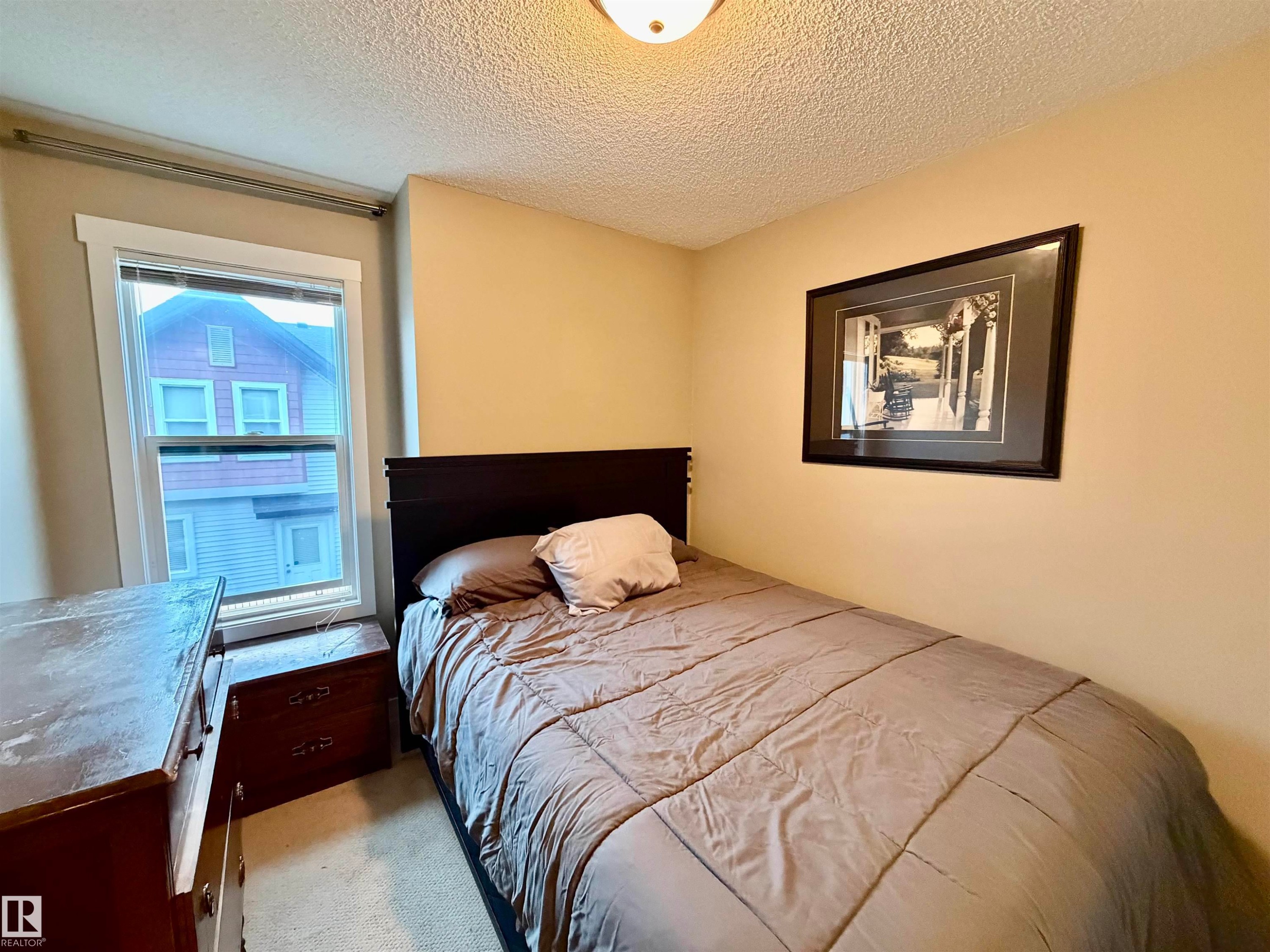 Bedroom featuring neutral wall paint, white trim, a single window, and textured ceiling - 45 6075 Schonsee Way, Edmonton, AB