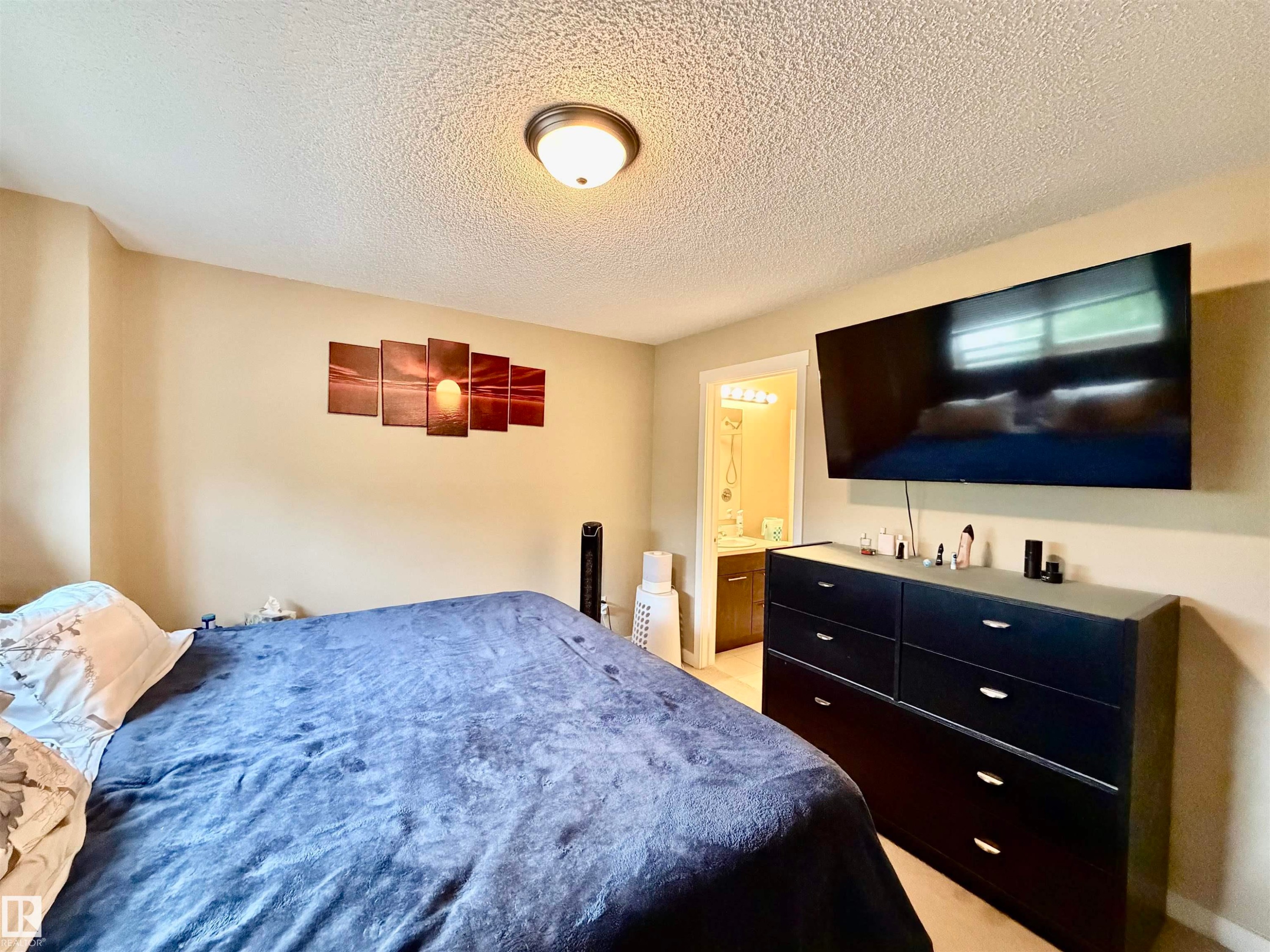 Bedroom featuring light beige wall color, textured ceiling, and a flush-mount ceiling light fixture - 45 6075 Schonsee Way, Edmonton, AB