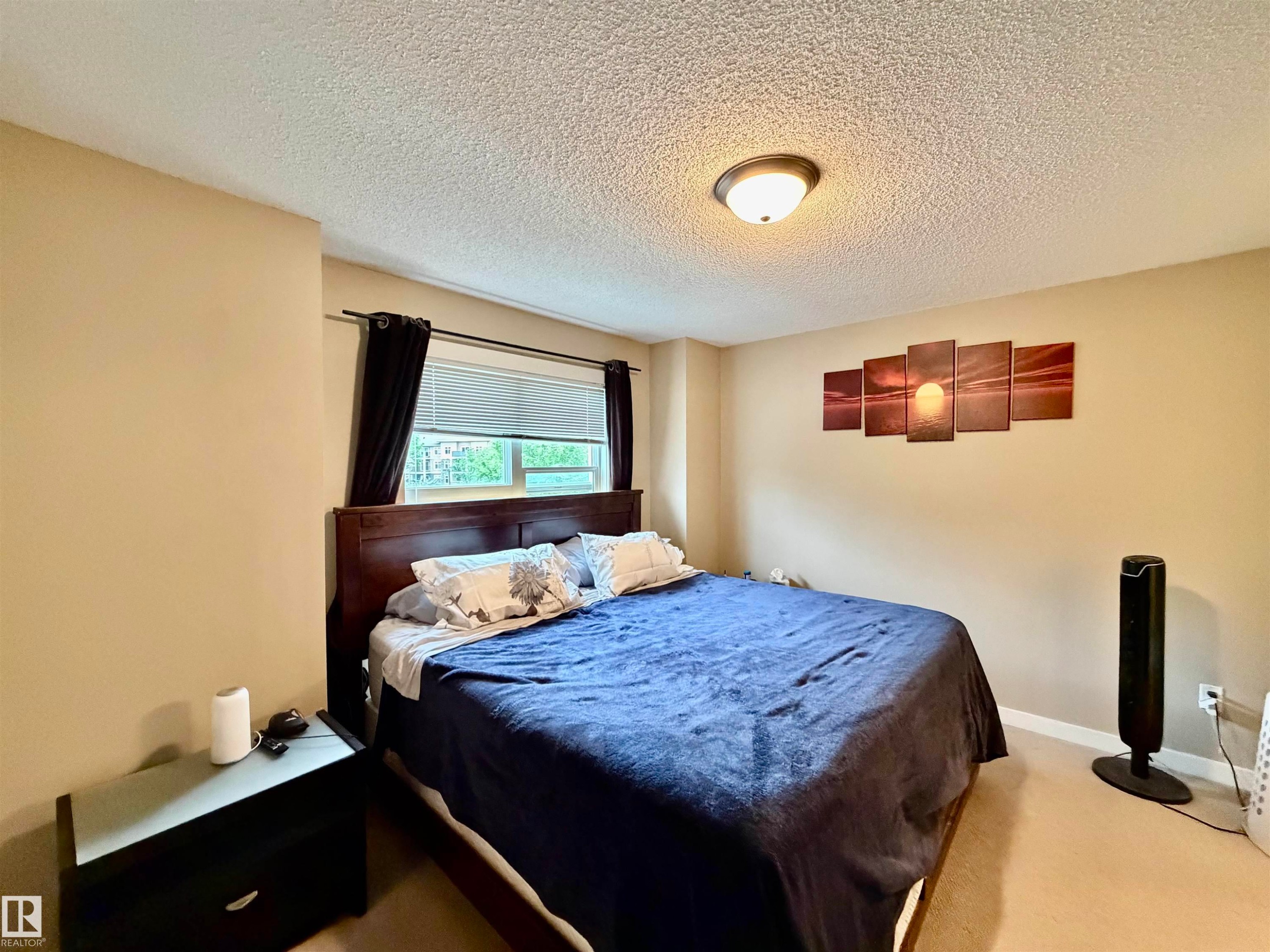 Bedroom featuring a large window, neutral paint, and ceiling-mounted lighting - 45 6075 Schonsee Way, Edmonton, AB