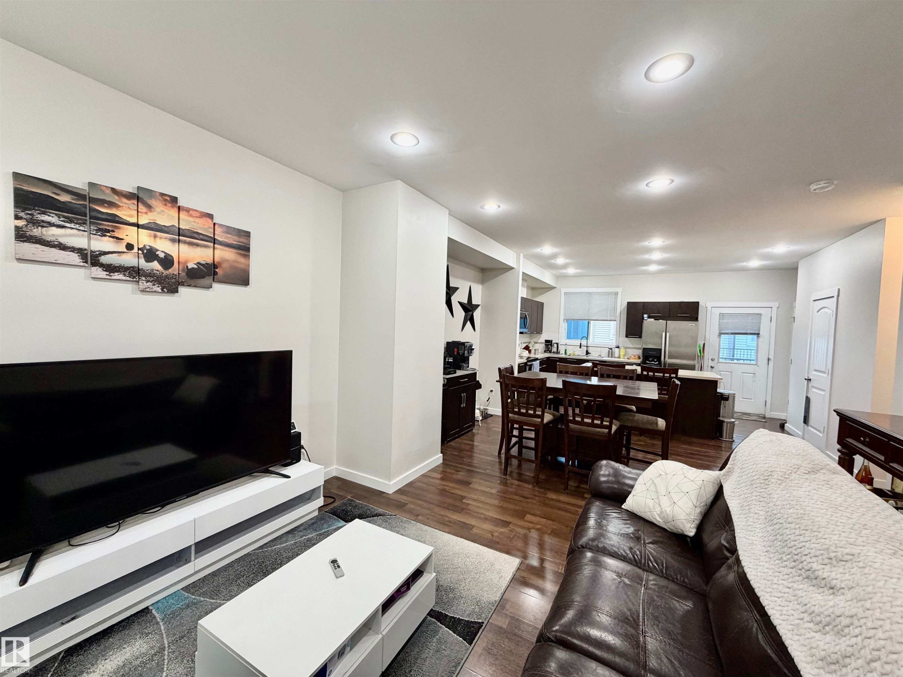 Open-concept living space featuring wood-finish flooring, recessed lighting, and white walls - 45 6075 Schonsee Way, Edmonton, AB