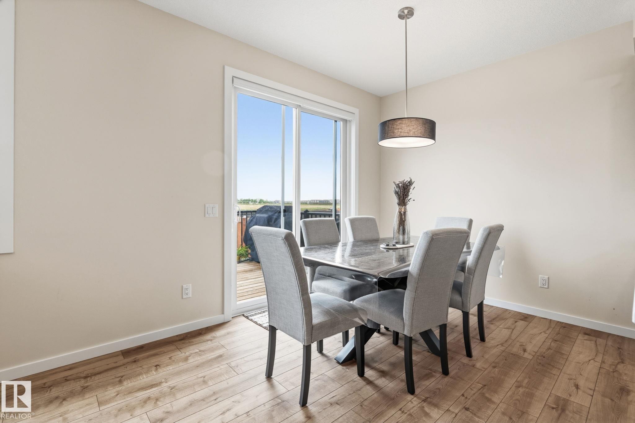 Bright room with wood-finish flooring, featuring a sliding glass door providing exterior access - 20011 26, Edmonton, AB