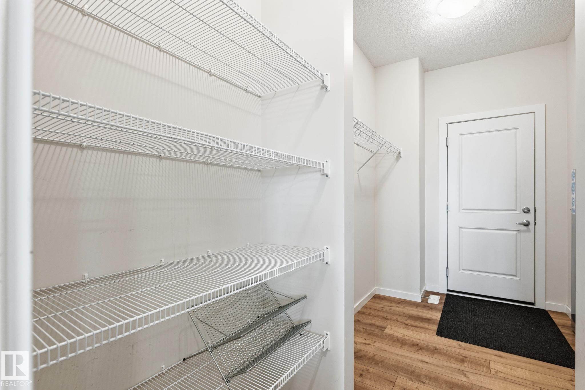 Entryway featuring wood-finish flooring, a white paneled door with brushed nickel hardware, and a ceiling-mounted light fixture - 20011 26, Edmonton, AB