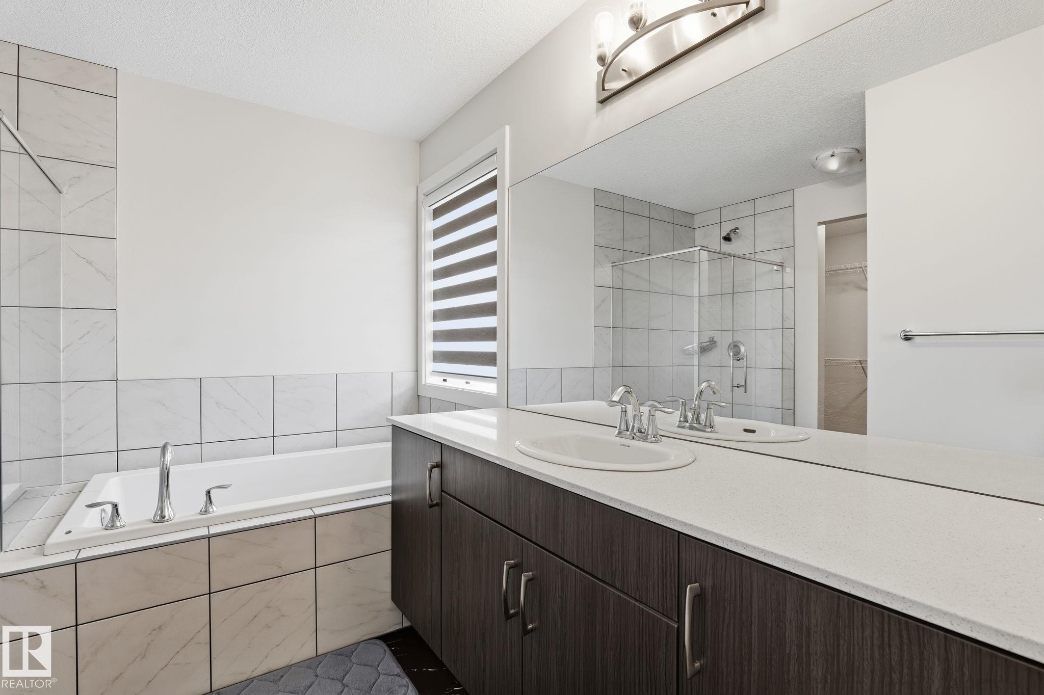 Bathroom featuring a dual vanity with a light-toned countertop, integrated sinks, and dark wood-finish cabinetry - 20011 26, Edmonton, AB