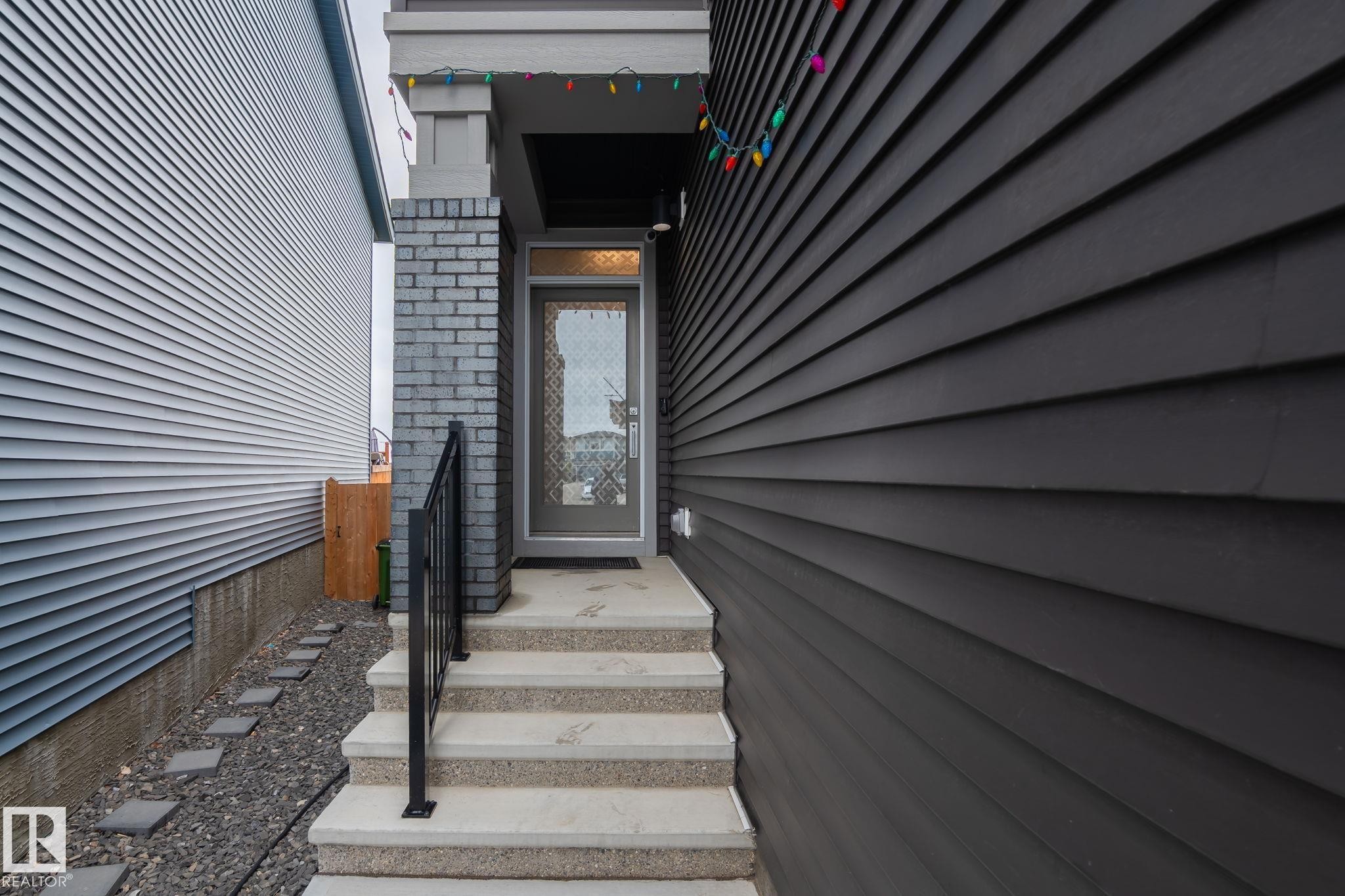 Concrete steps with a black metal handrail leading to the front entry - 20011 26, Edmonton, AB