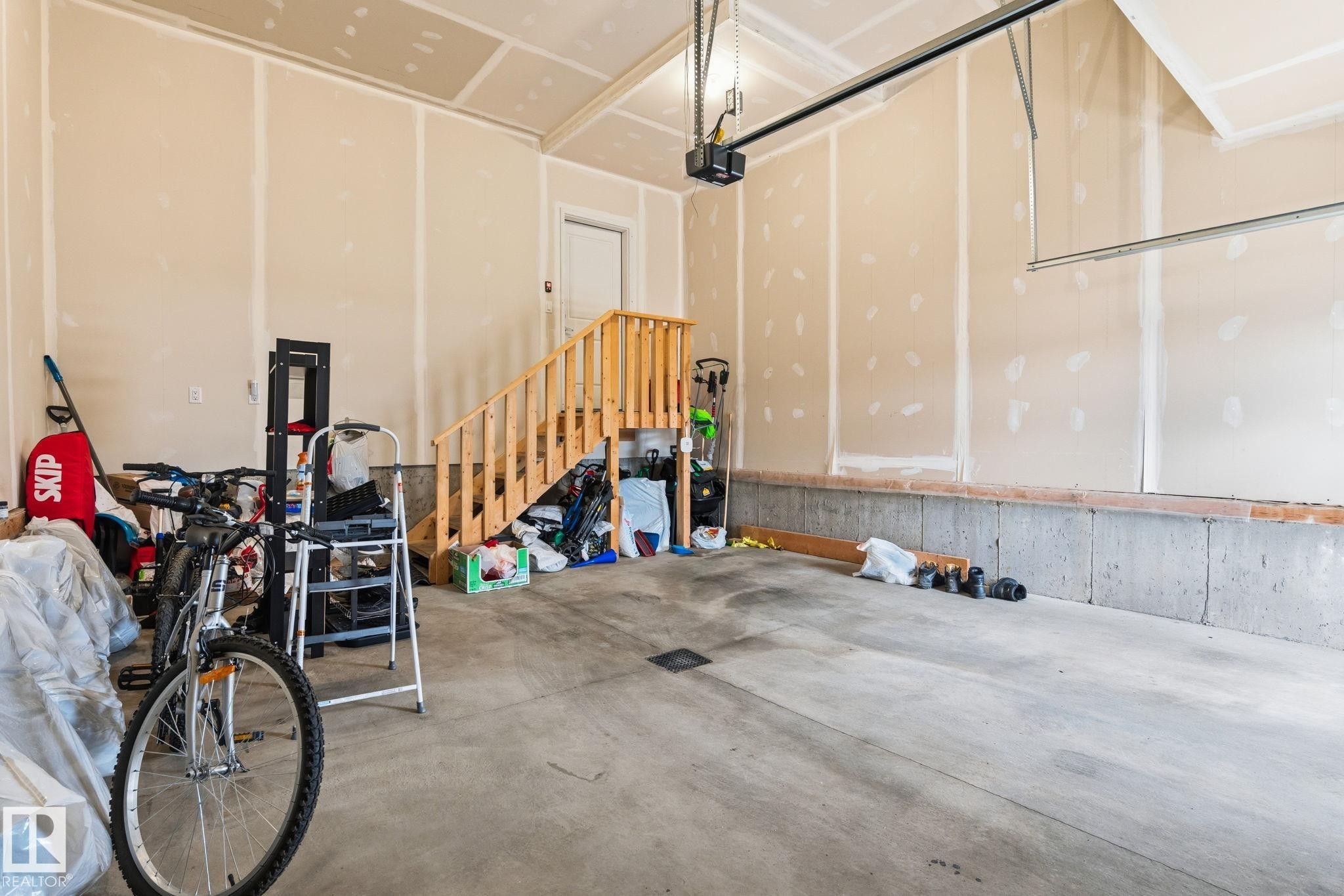 Concrete flooring in an unfinished garage with wood stairs and a garage door opener system - 20011 26, Edmonton, AB