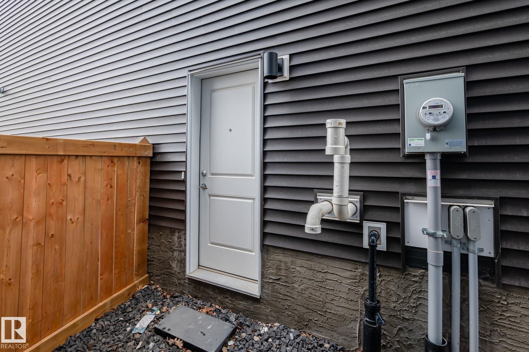Exterior wall featuring horizontal siding, a white entry door, and a utility meter - 20011 26, Edmonton, AB