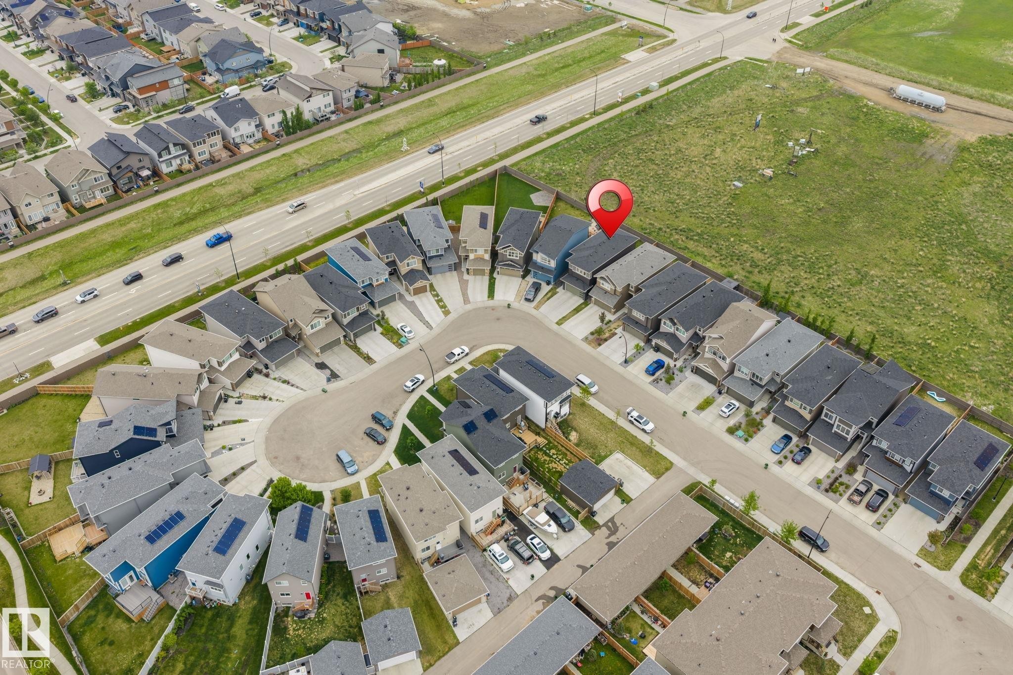 Aerial view of a residential community featuring a cul-de-sac and grid-pattern street layout, with properties bordering undeveloped land - 20011 26, Edmonton, AB
