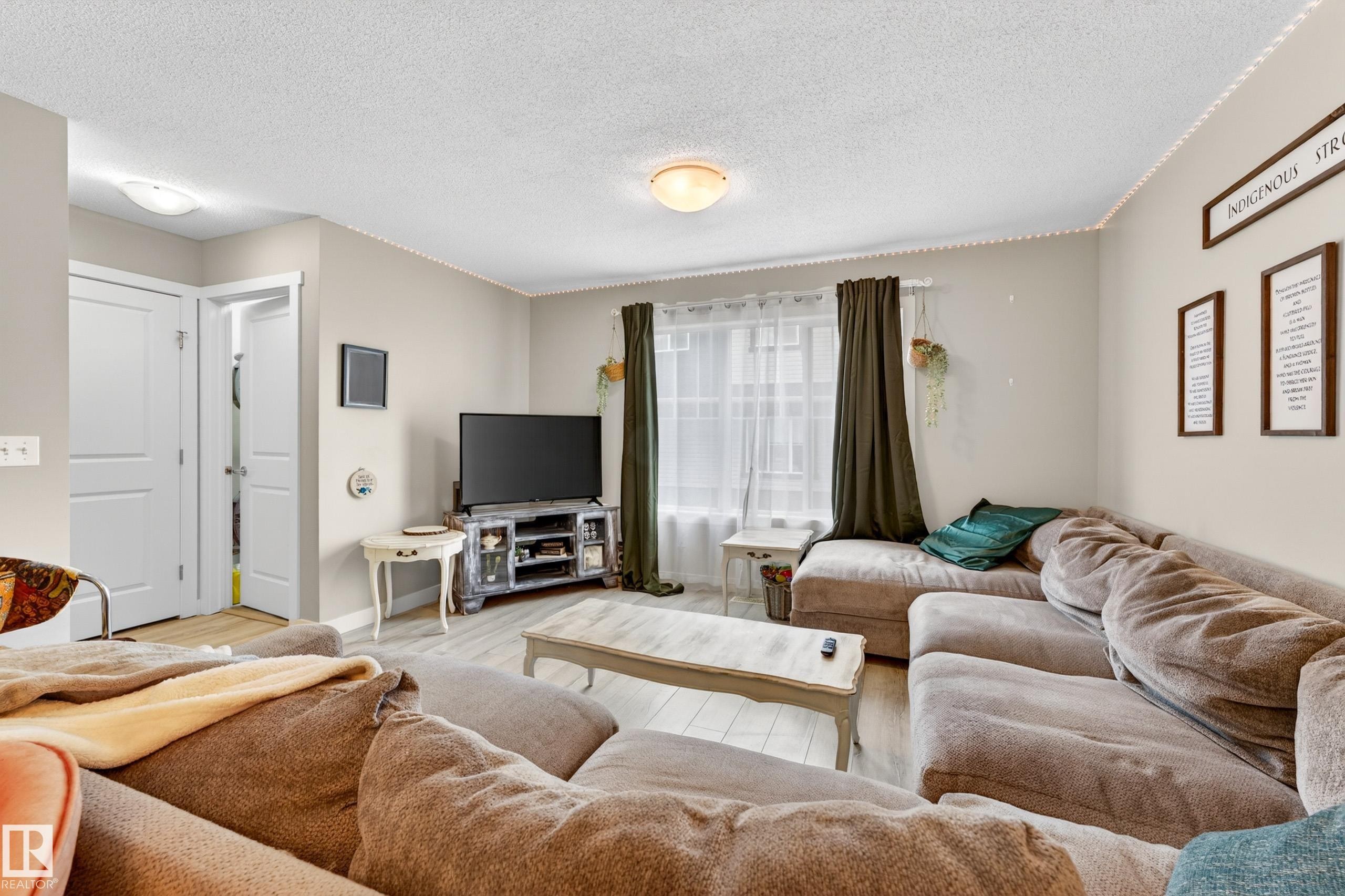 Spacious living area featuring light-toned walls and wood-finish flooring - 85 165 Cy Becker Boulevard, Edmonton, AB - Indoor Photo Showing Living Room