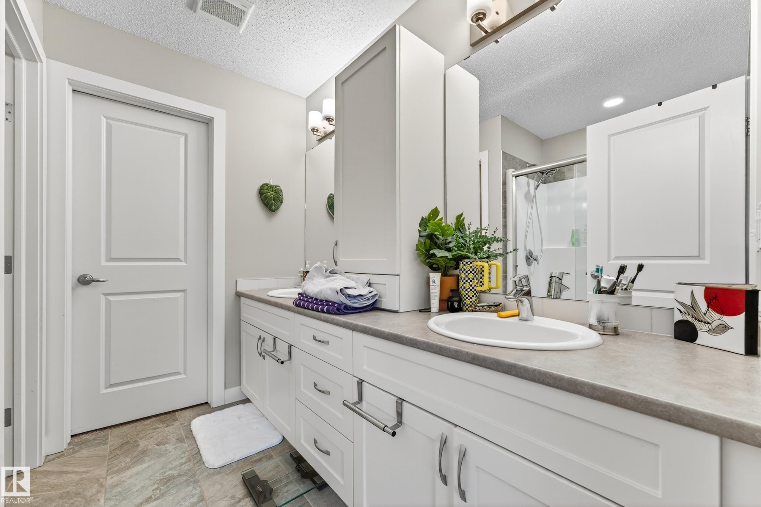 Dual white vanities with integrated sinks, ample storage cabinetry, and a full-width mirror - 85 165 Cy Becker Boulevard, Edmonton, AB - Indoor Photo Showing Bathroom