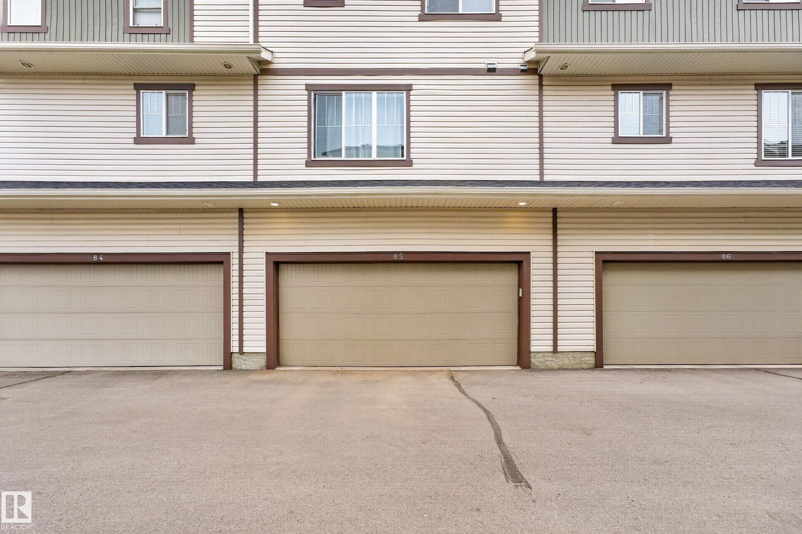 Three individual garage doors with brown trim - 85 165 Cy Becker Boulevard, Edmonton, AB - Outdoor With Exterior