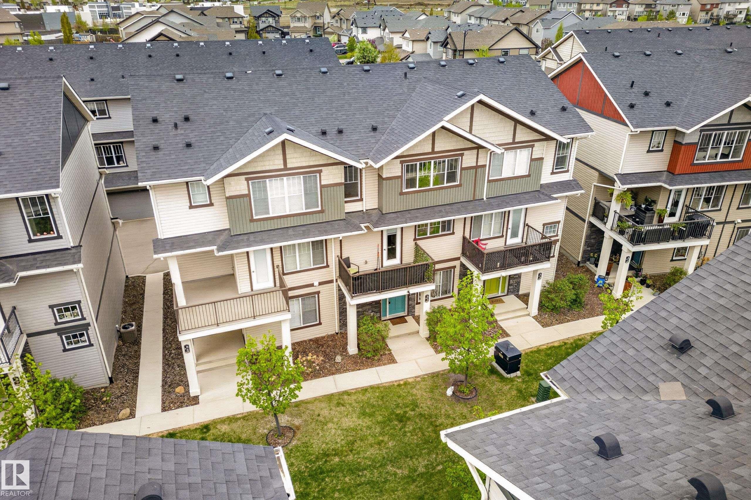 Multi-level townhome featuring a neutral-toned facade with contrasting trim, multiple balconies, and a covered entry porch - 85 165 Cy Becker Boulevard, Edmonton, AB - Outdoor With Facade