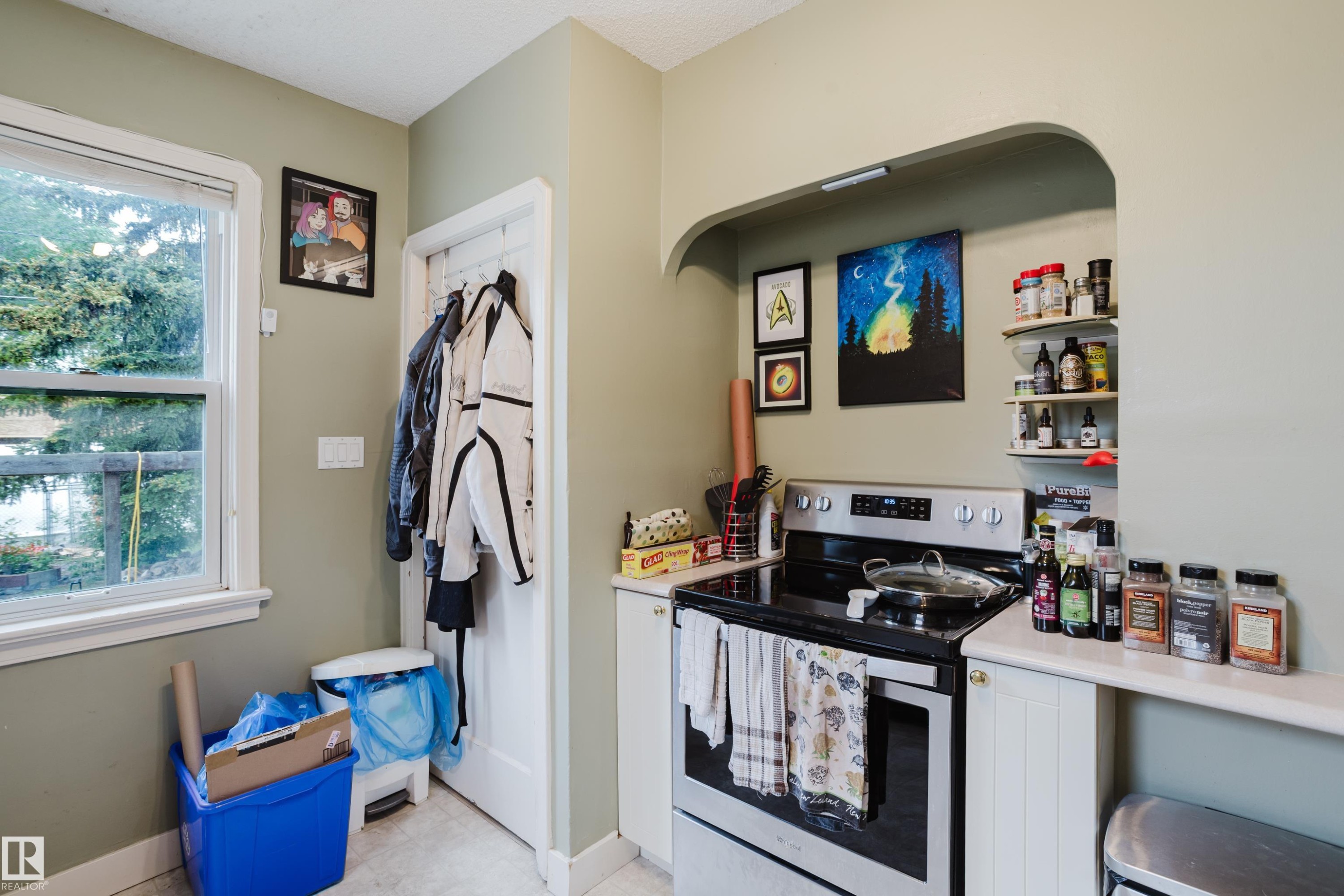Stainless steel electric range with a black ceramic cooktop, integrated into an arched wall niche with open shelving - 11158 65 Street, Edmonton, AB