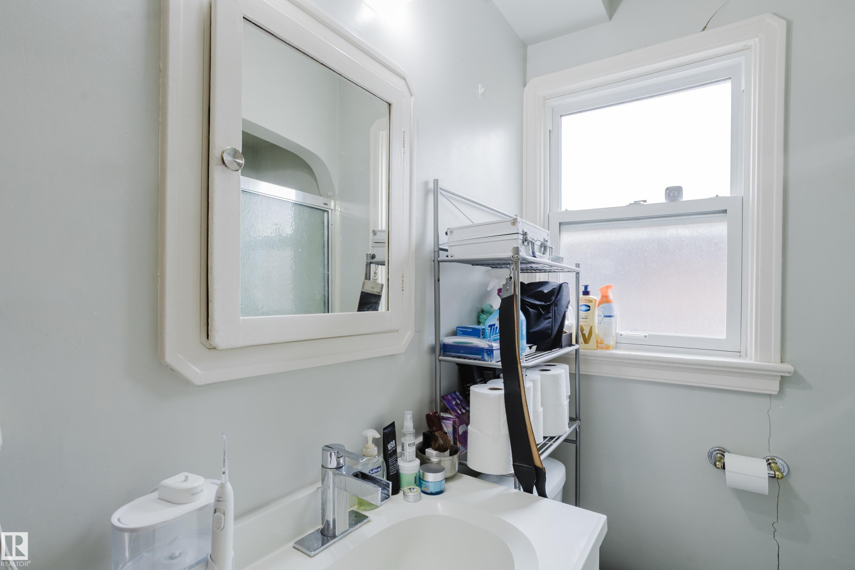 Bathroom vanity with a single basin, chrome faucet, and integrated mirror cabinet - 11158 65 Street, Edmonton, AB