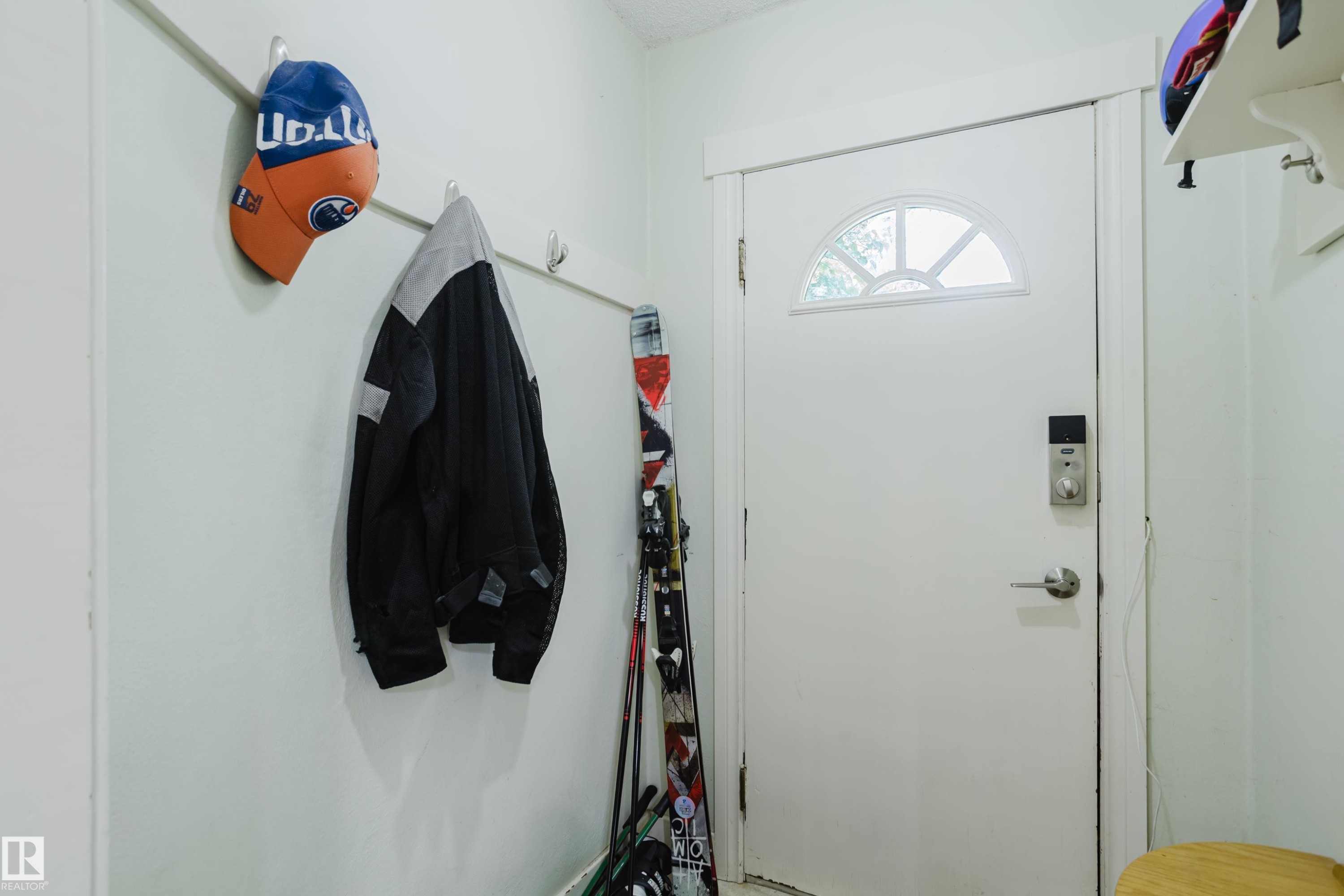 Entry door featuring a decorative arched window pane and a smart lock system - 11158 65 Street, Edmonton, AB