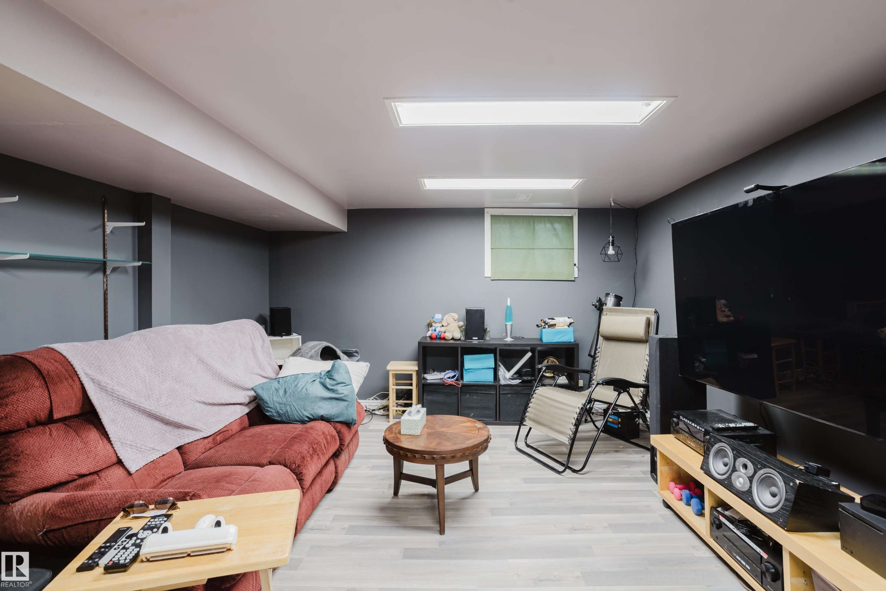 Finished living space featuring light wood-finish flooring, recessed lighting, and a window with blinds - 11158 65 Street, Edmonton, AB