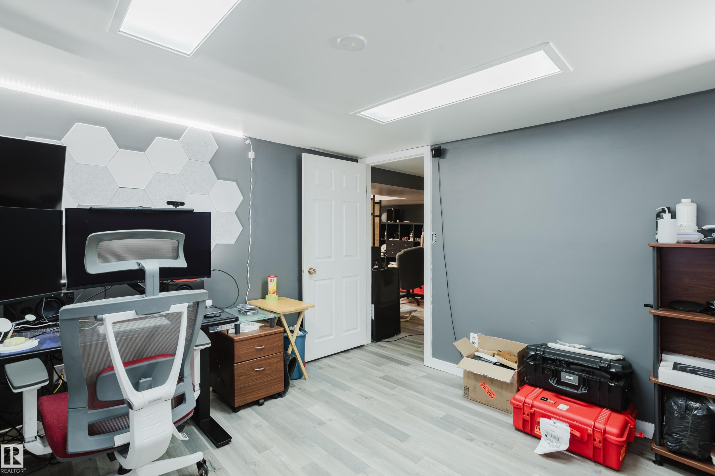 Room featuring light gray walls and wood-finish flooring, with two recessed rectangular ceiling lights and a white paneled door - 11158 65 Street, Edmonton, AB